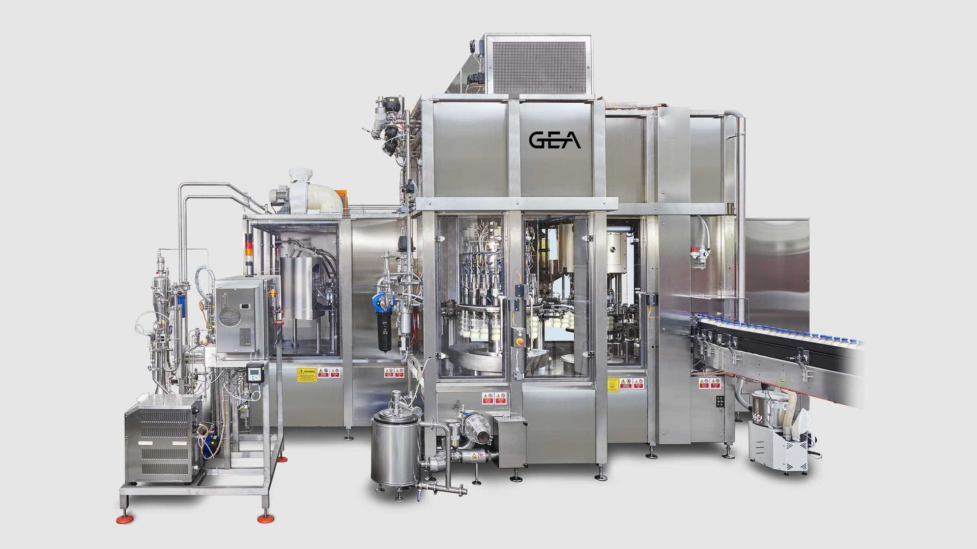 Large GEA stainless steel industrial bottling and filling machine with conveyor belt and bottles.