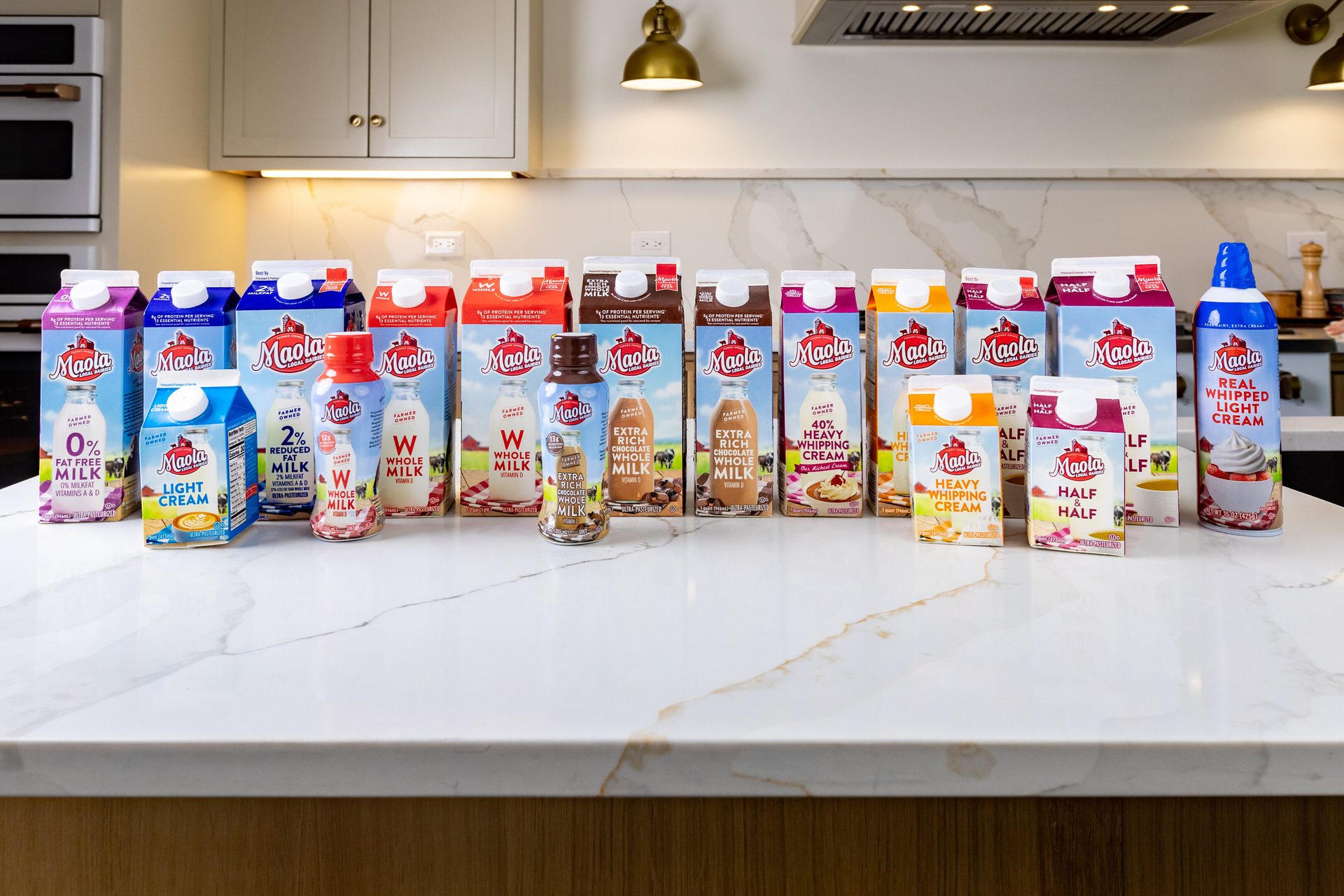 A variety of Maola dairy products, including milk, cream, and whipped cream, are displayed on a kitchen counter.