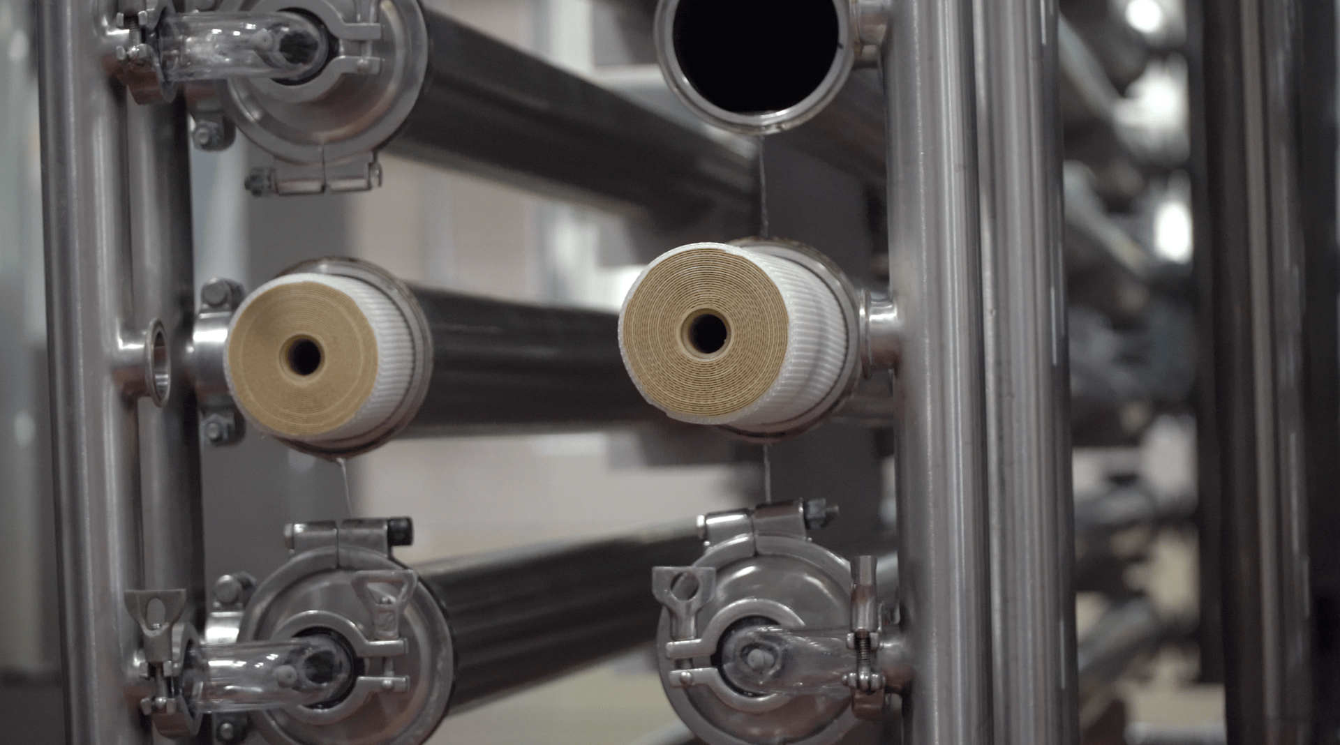 Stainless steel industrial water filter system with two rolled filters and a clear UV light component.