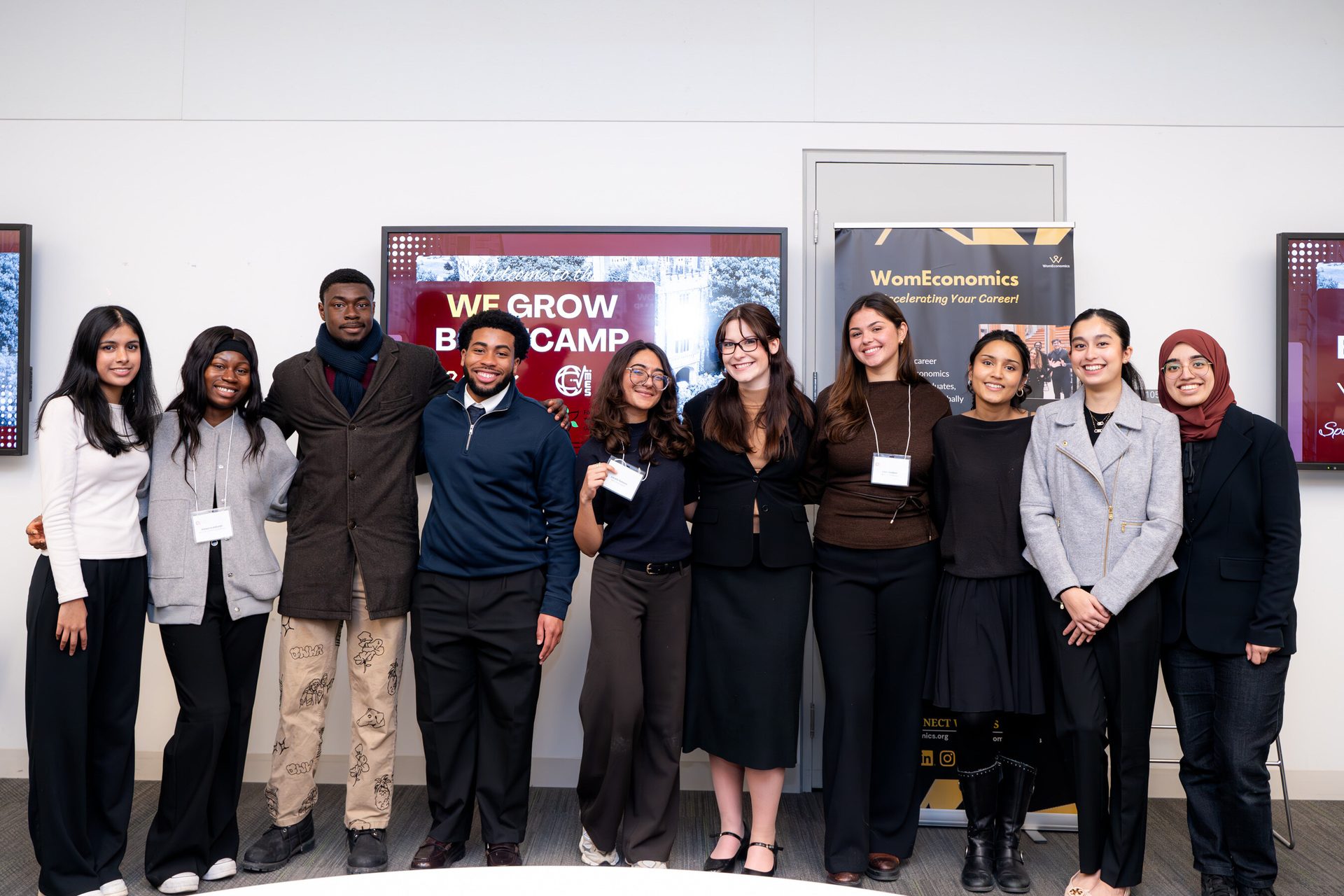 Ten young adults, diverse in ethnicity, smile for a group photo at an event.
