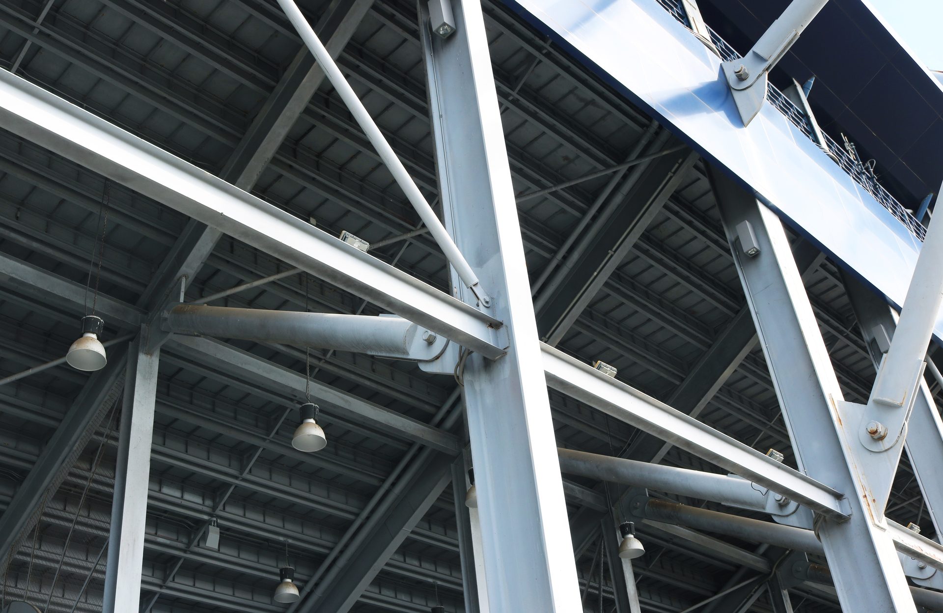 Large grey metallic structure from below, showing intersecting beams and blue upper section.