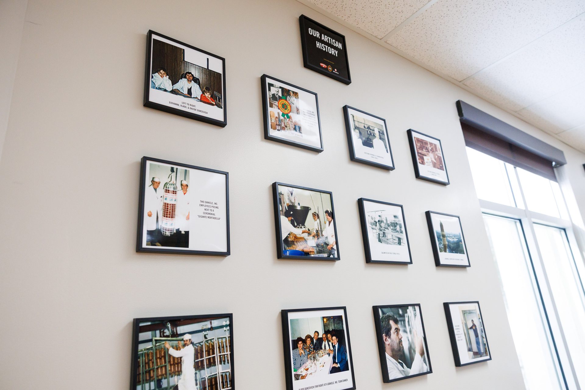 A wall adorned with numerous framed photos, depicting the artisan history and processes of a company.