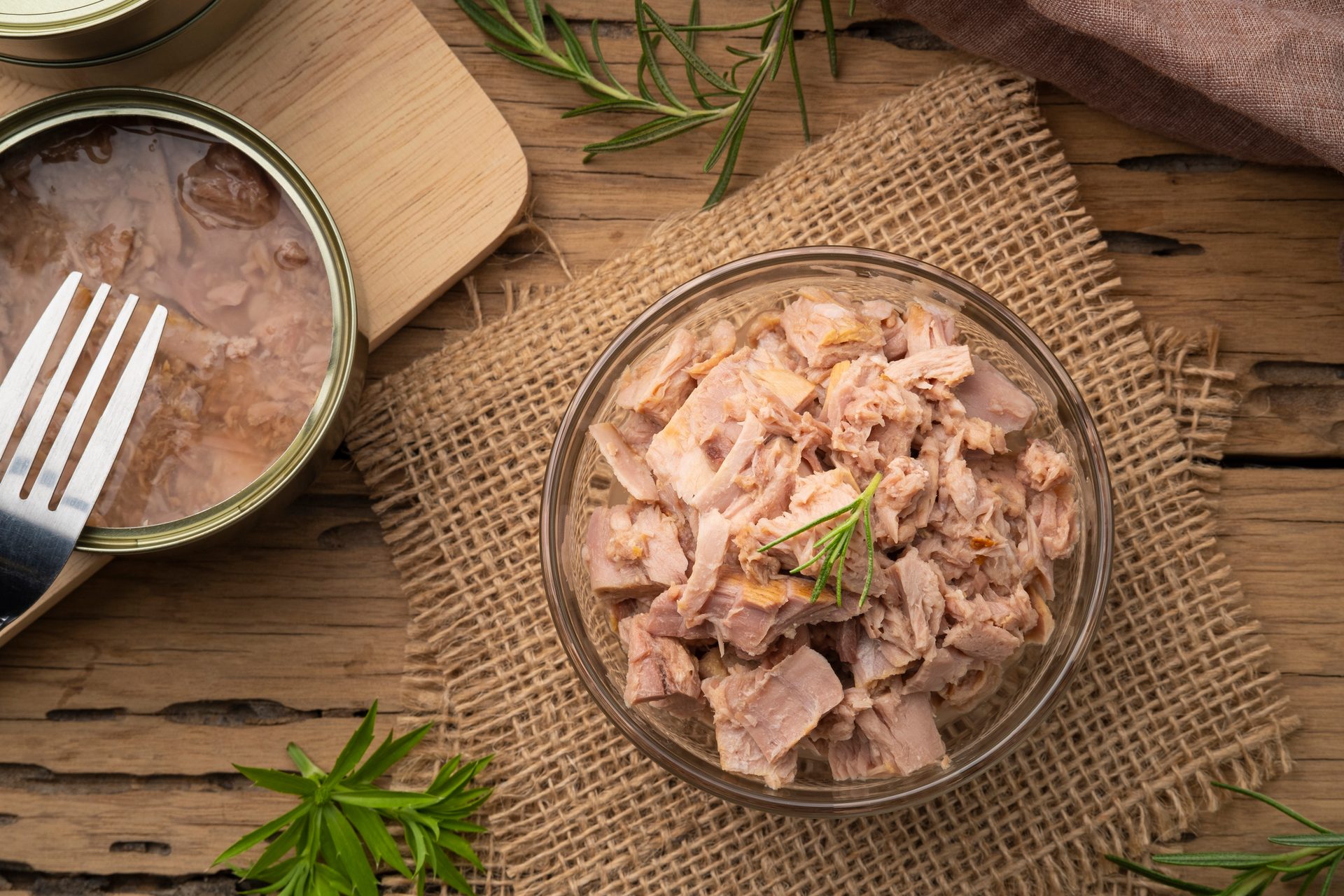 Canned tuna and tuna flakes in a glass bowl.