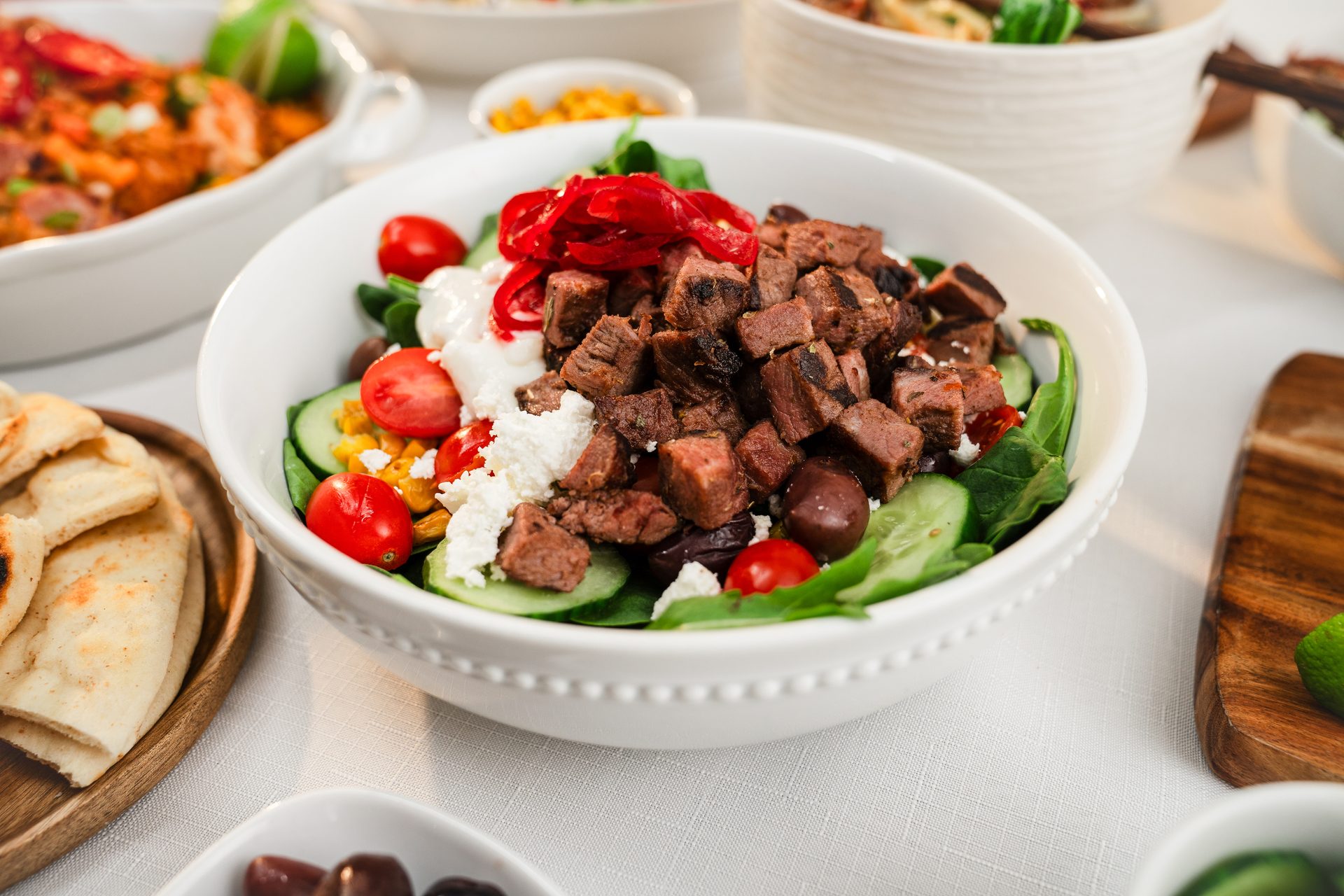Colorful steak salad with cubed steak, tomatoes, cucumbers, feta, olives, and pickled red onions.