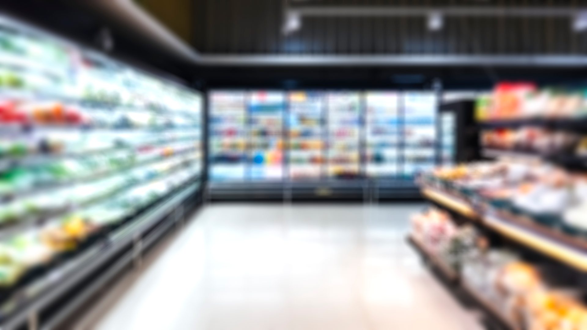 Blurred supermarket aisle with refrigerated sections and product displays.