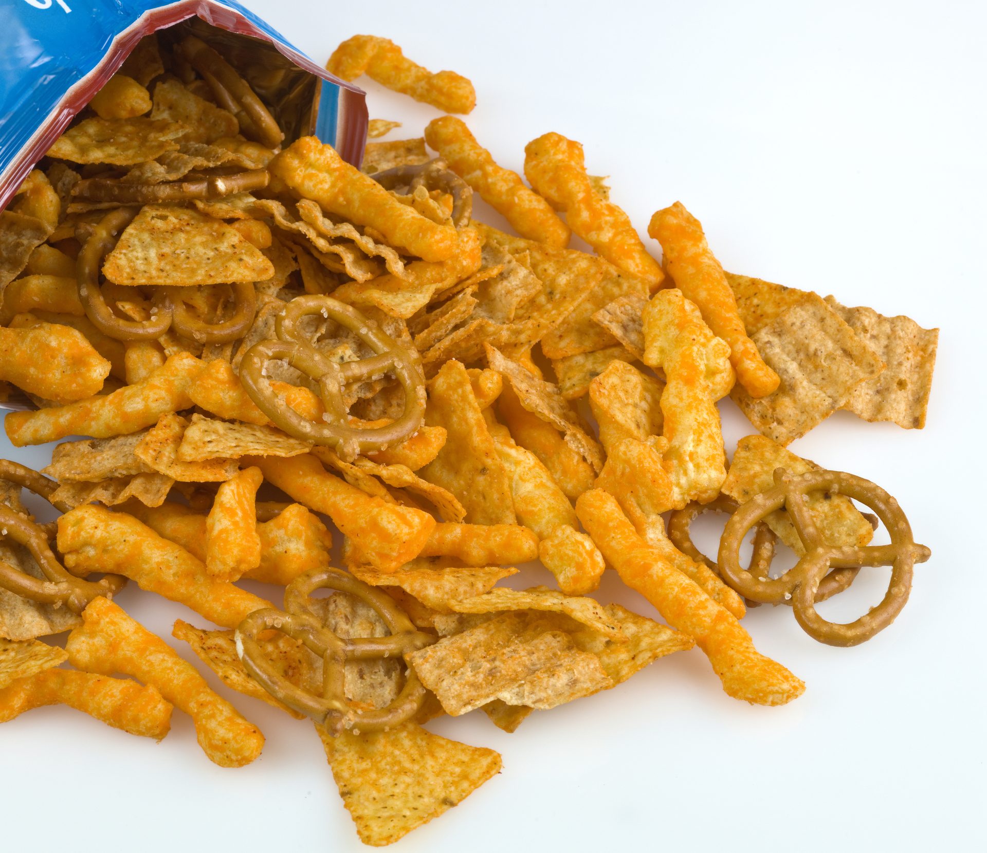Orange snack mix: pretzels, cheese puffs, and chips spill from bag.