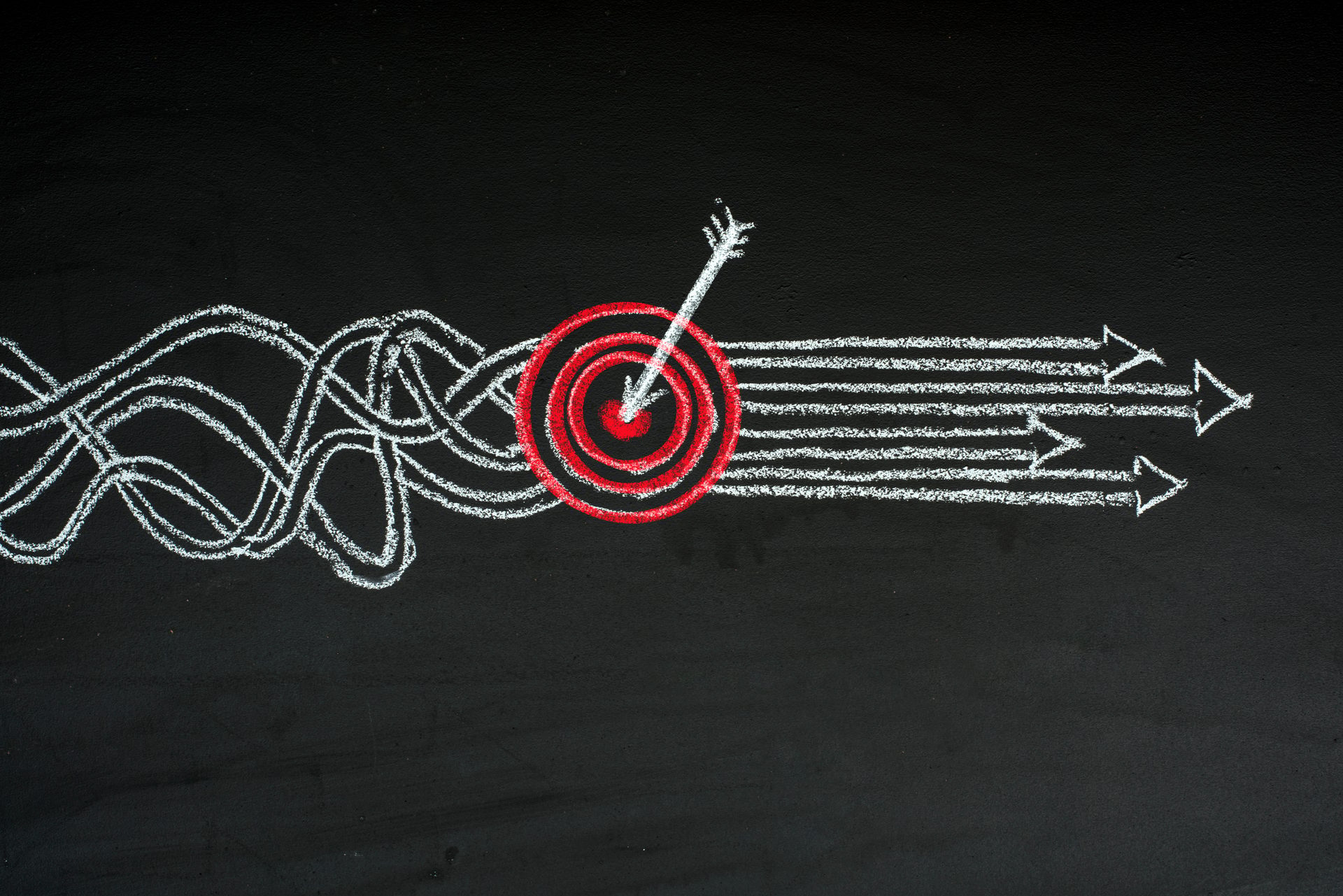 Chalk drawing: Tangled white lines converge, hitting a red target with an arrow, then becoming straight arrows.
