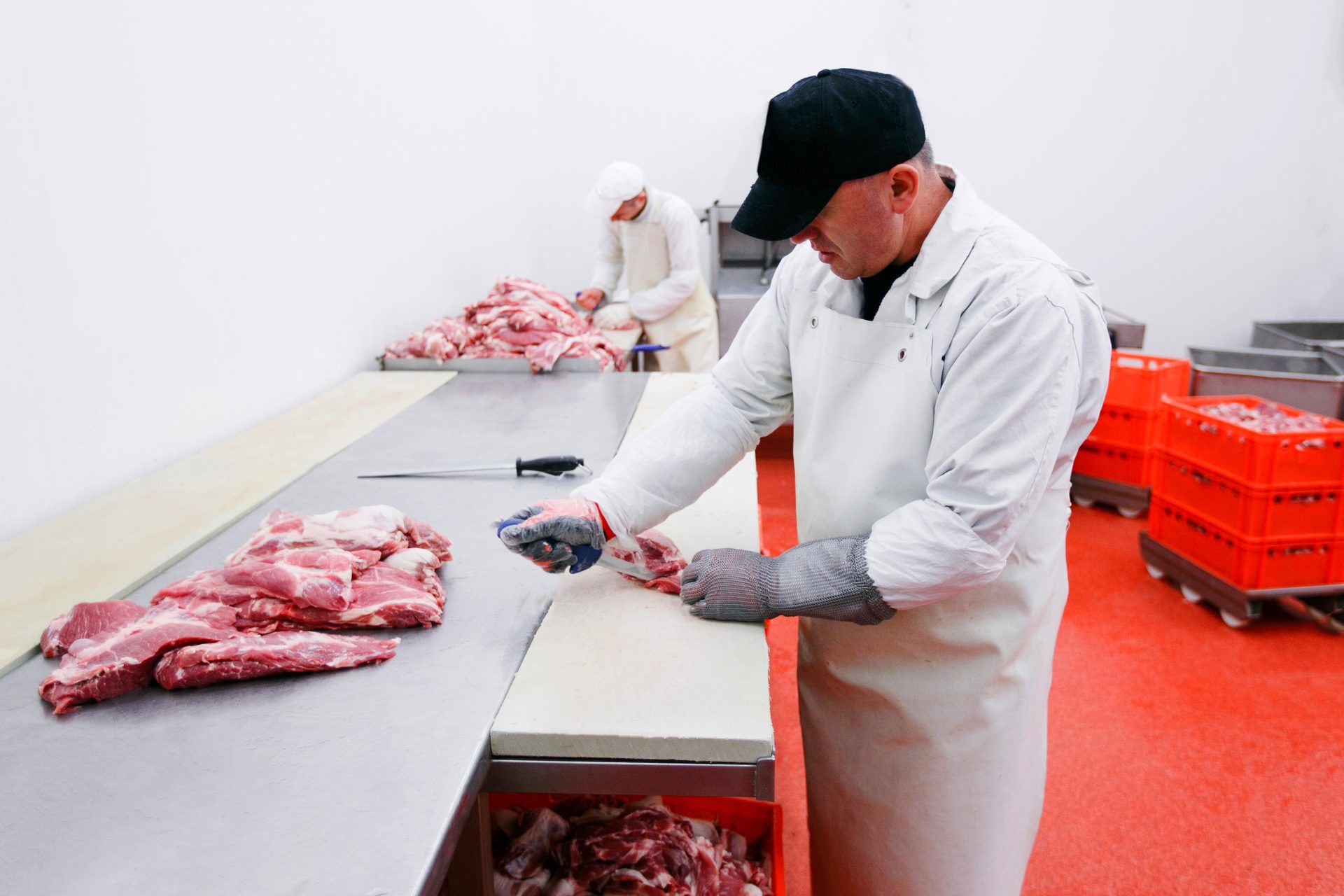 Butcher cutting meat in a processing plant.