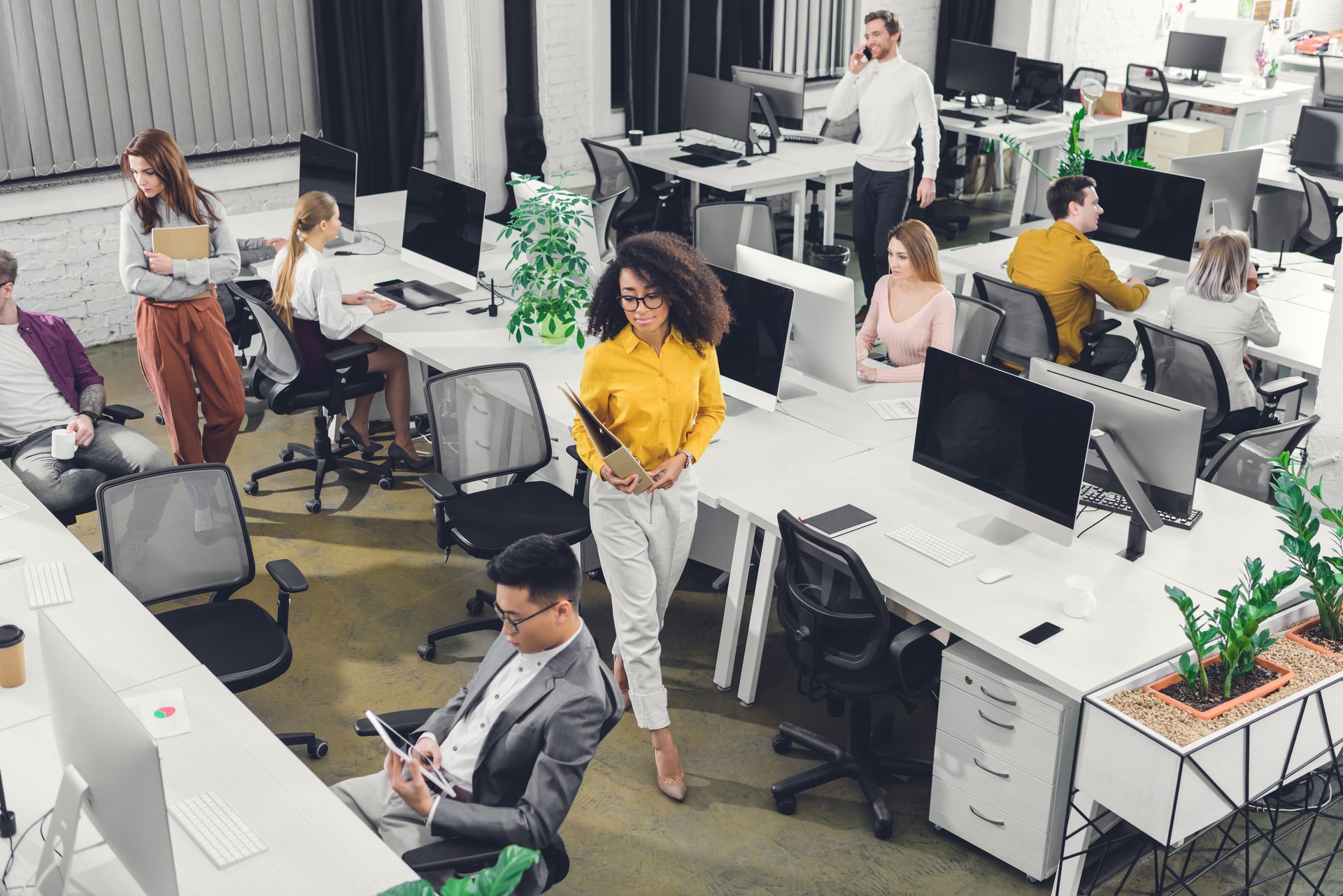 A diverse group of professionals working and interacting in a modern, open-plan office space.