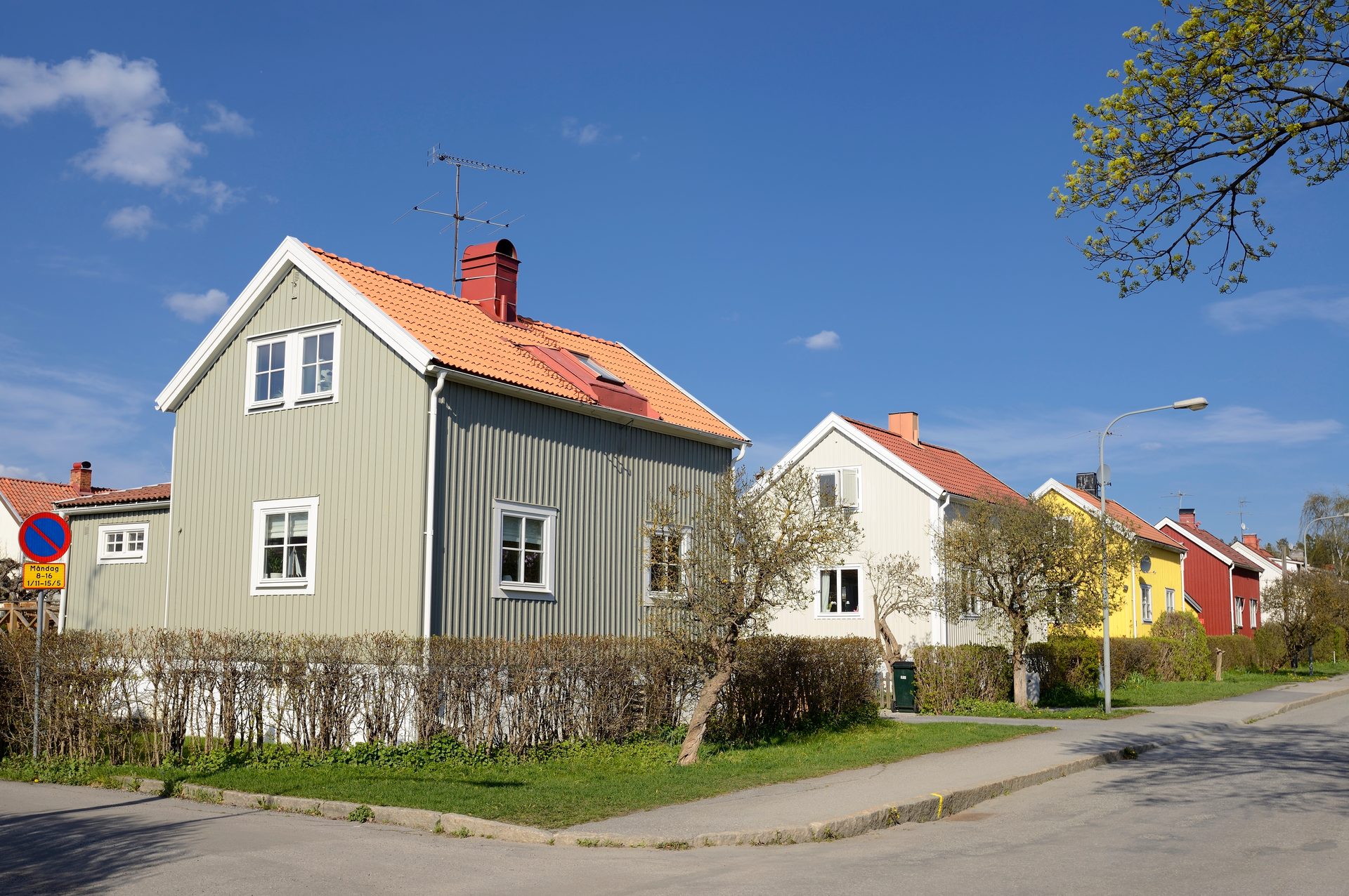 A street with a light green house and a row of colorful houses under a clear blue sky.