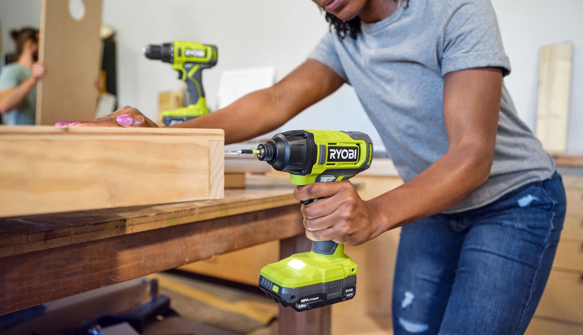 Person using a Ryobi impact driver to work on a wooden project.