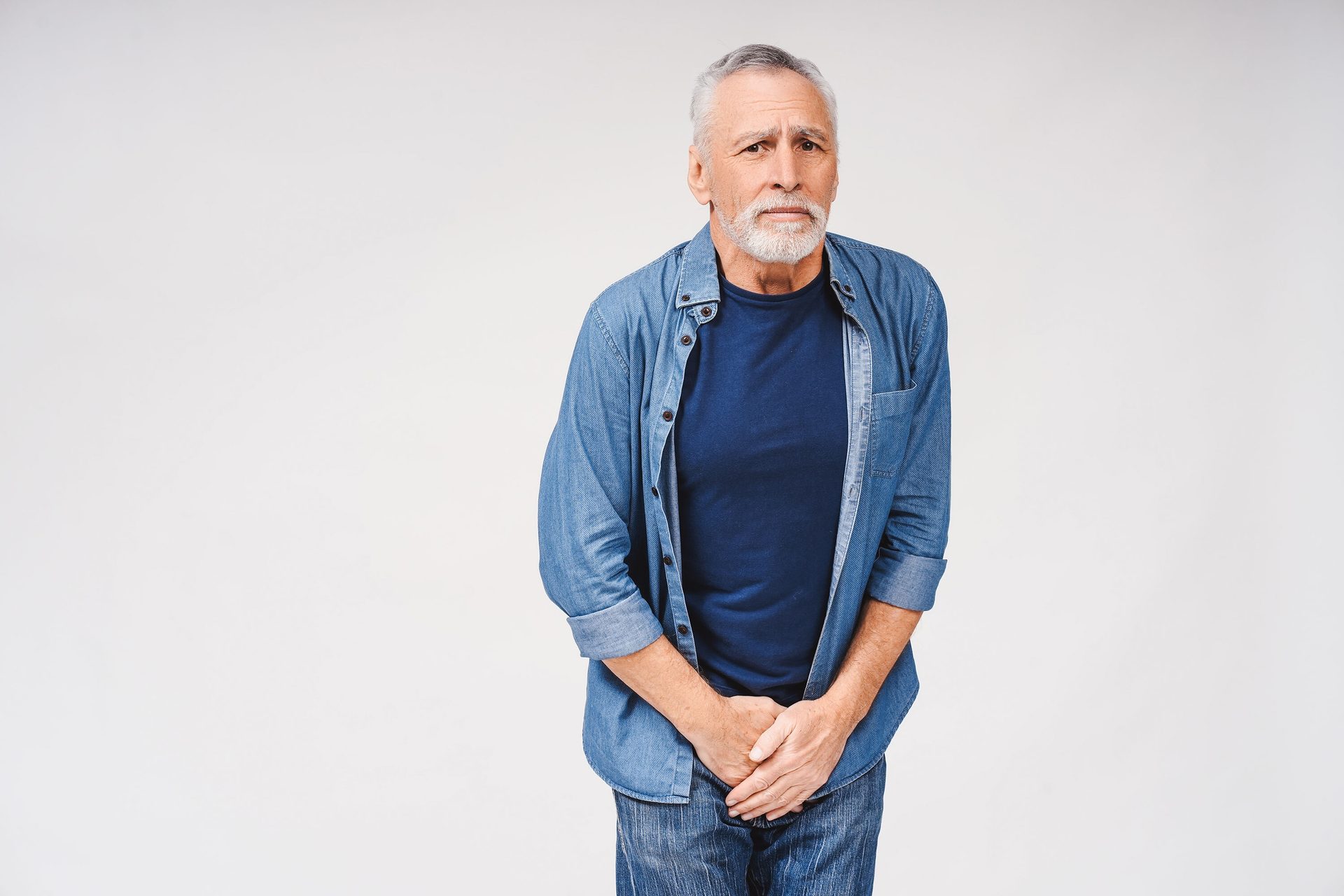 Distressed elderly man holding his groin, suggesting urinary discomfort.