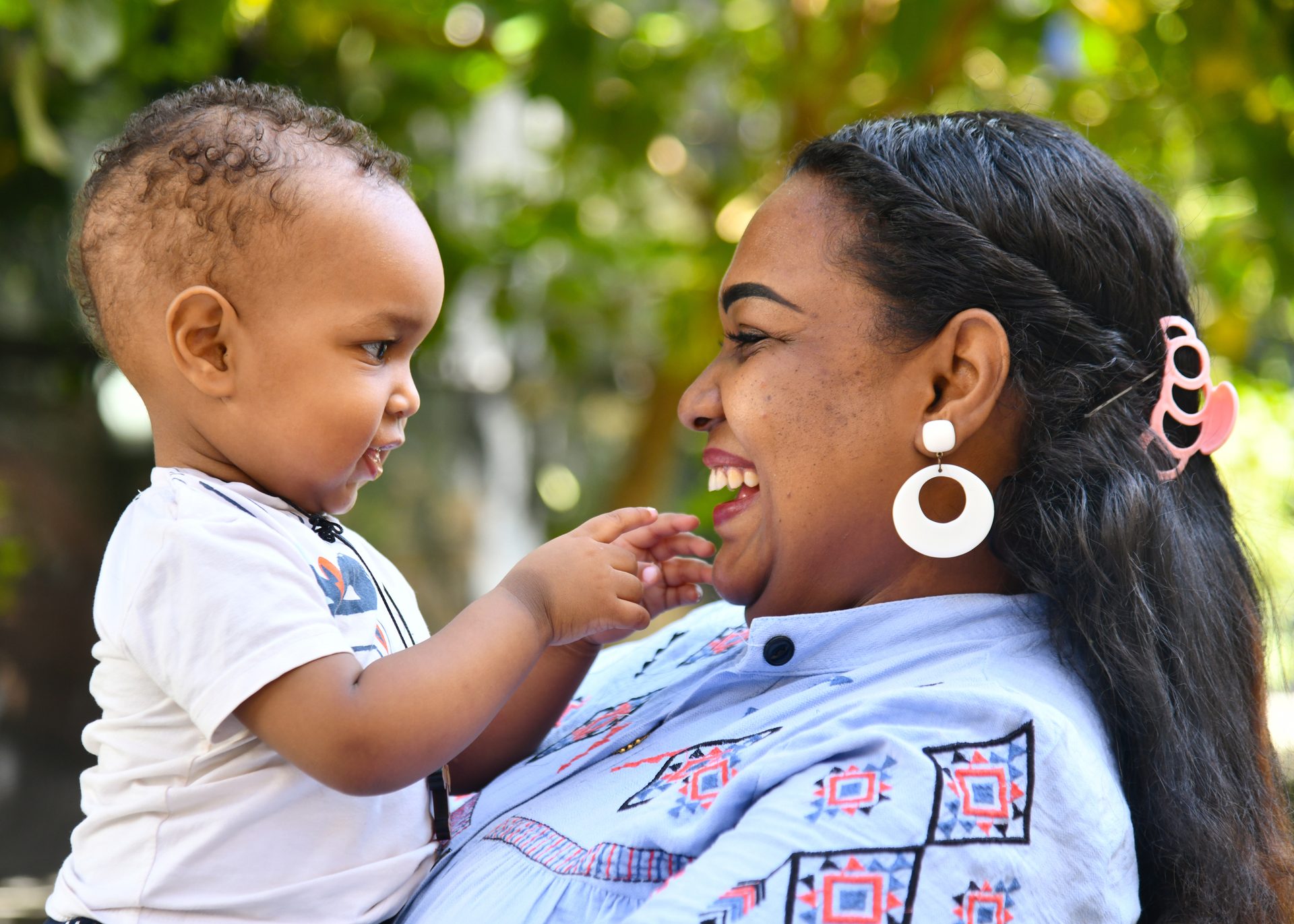 Smiling mother and baby bonding outdoors.
