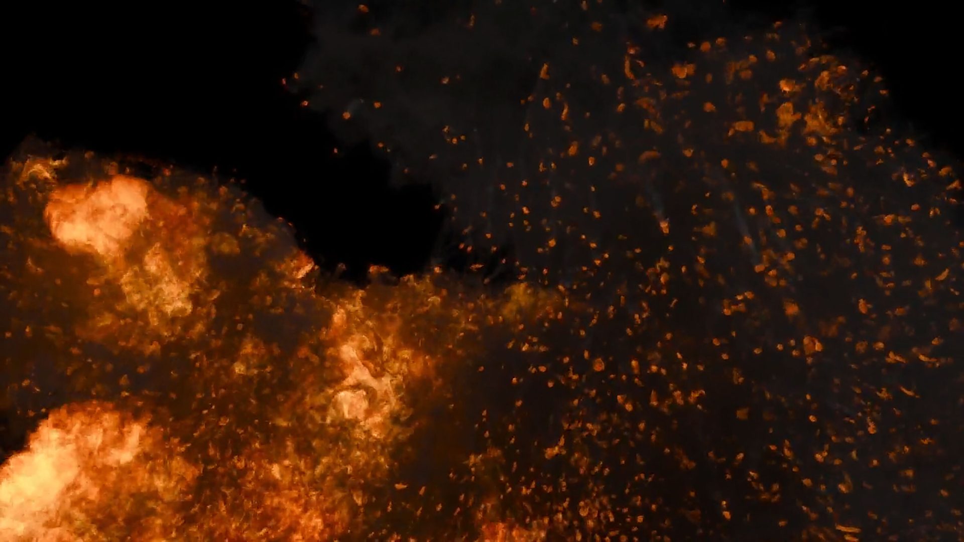 Orange and red fire with glowing embers and sparks against a dark background.
