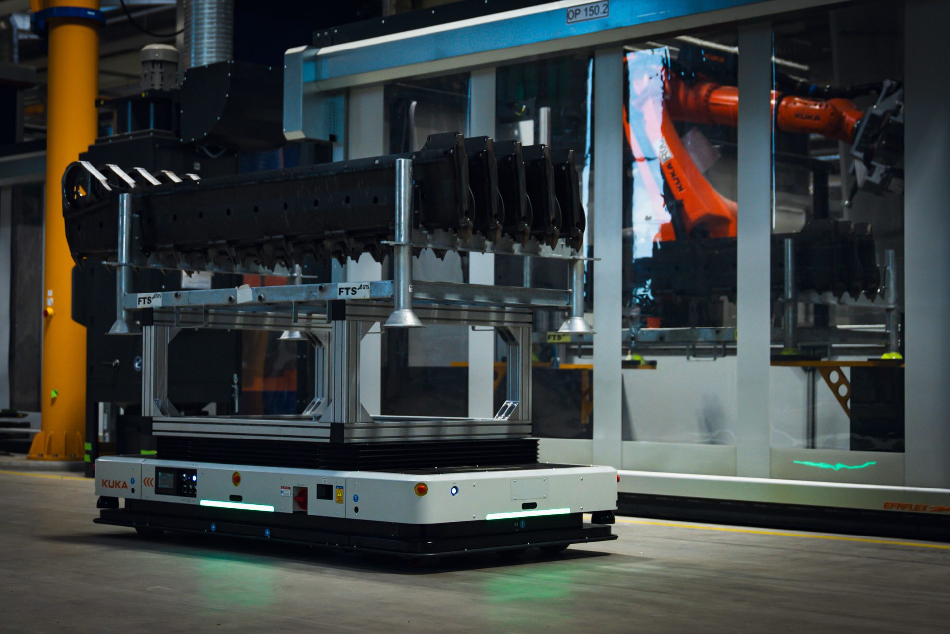 KUKA AGV transporting parts in a factory setting, with a KUKA robot arm visible in the background.