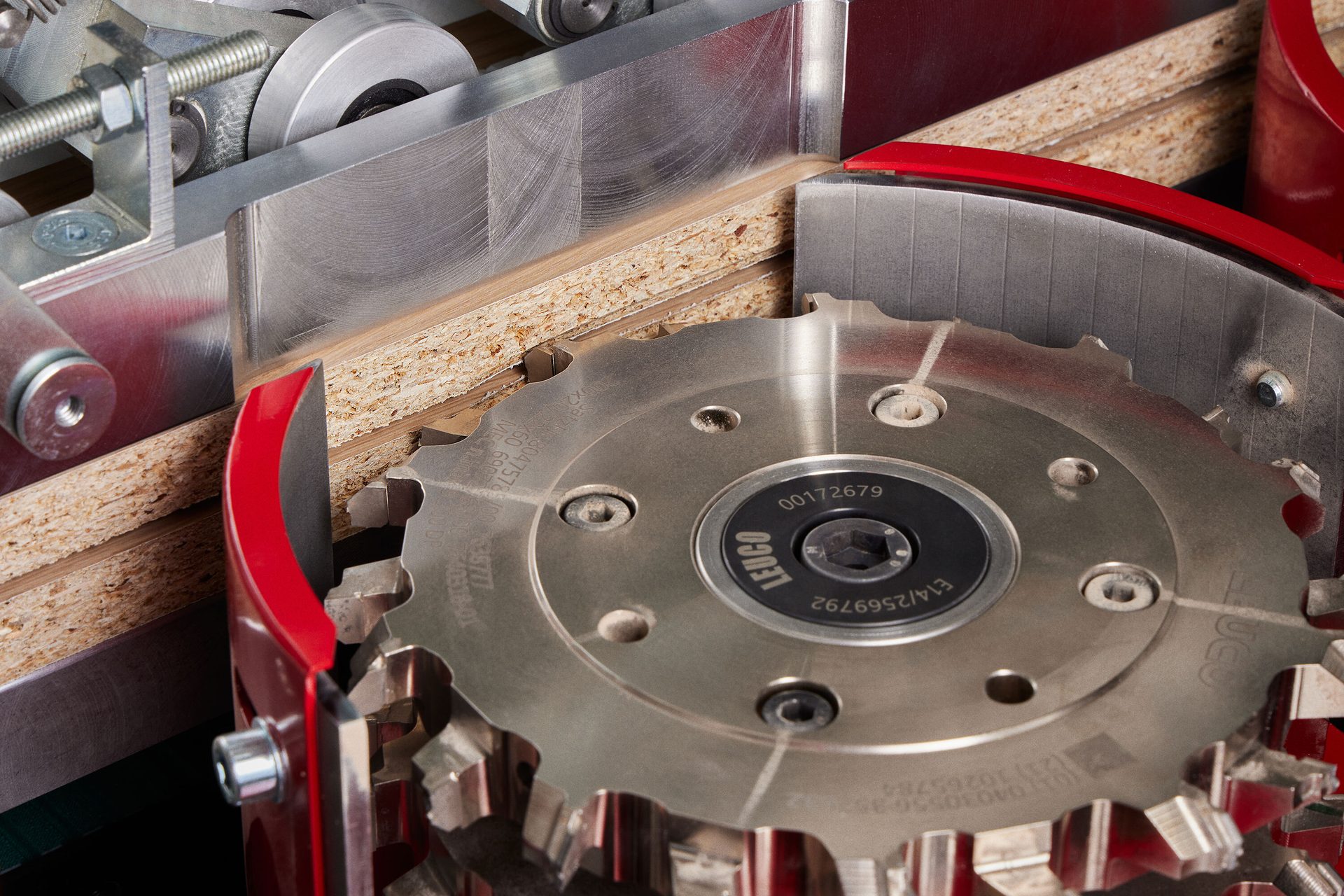 Close-up of a Leuco saw blade cutting particle board in a woodworking machine.
