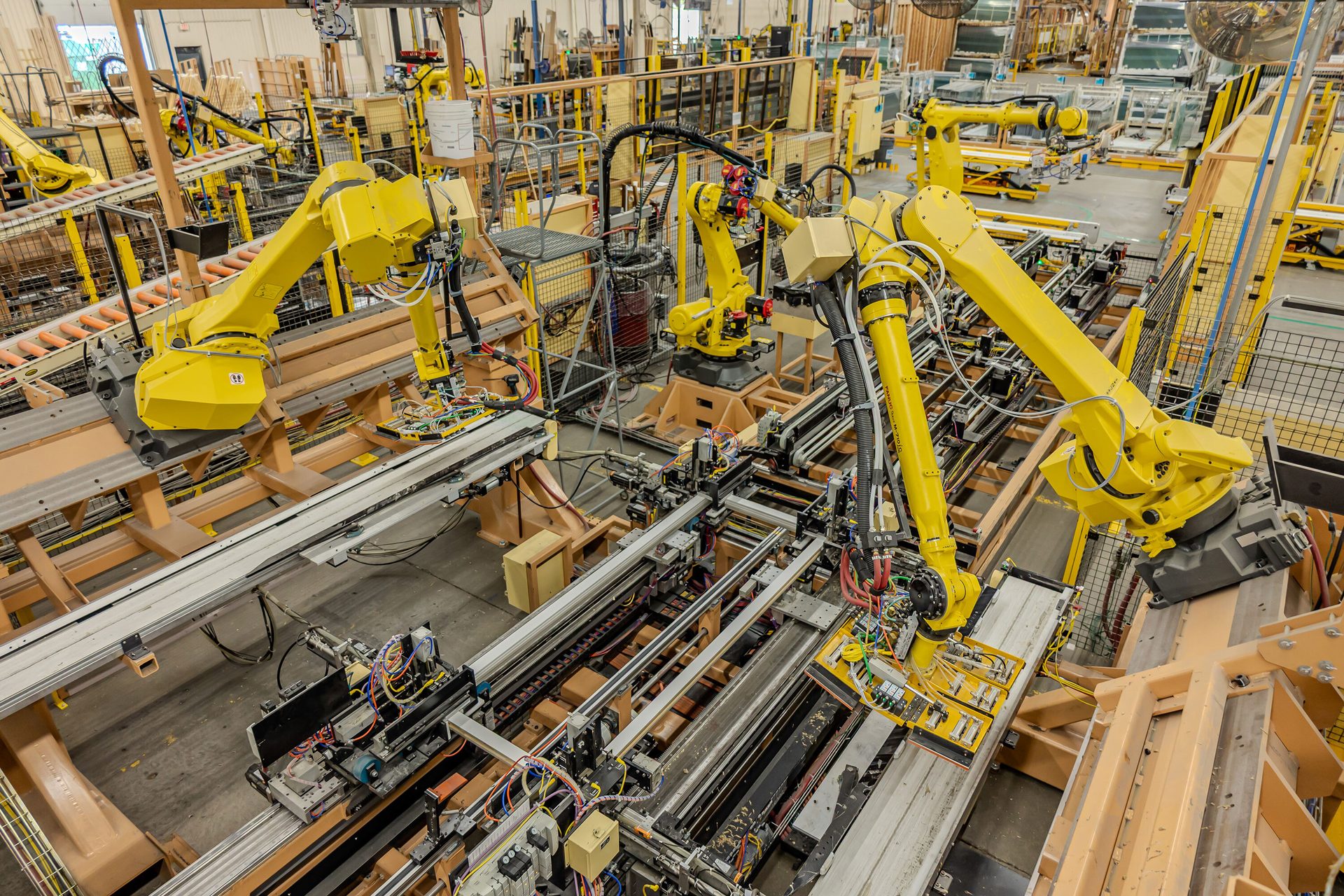 Industrial factory floor with multiple yellow robotic arms on an assembly line.