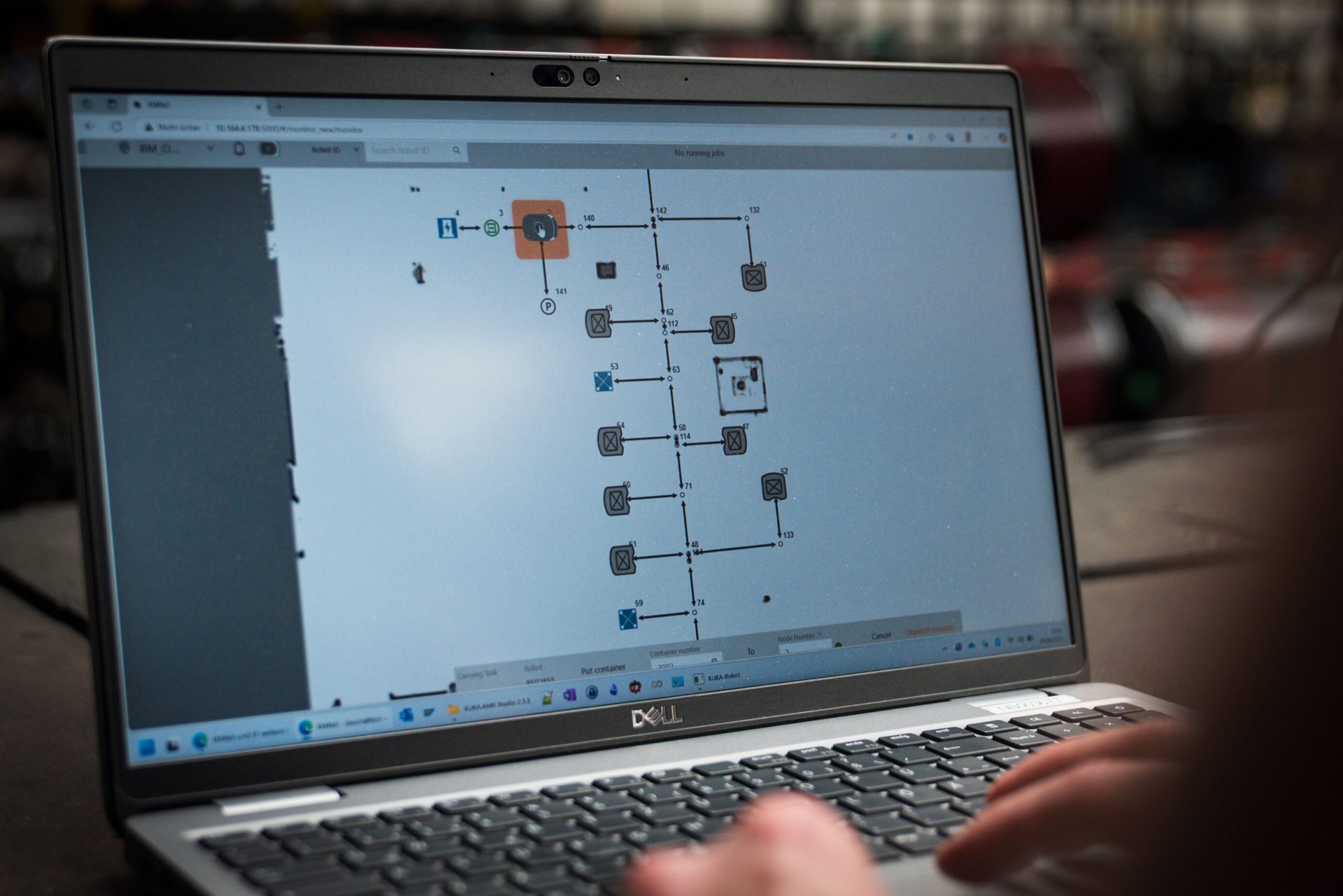 Person typing on a Dell laptop, screen shows a robotics process flowchart.