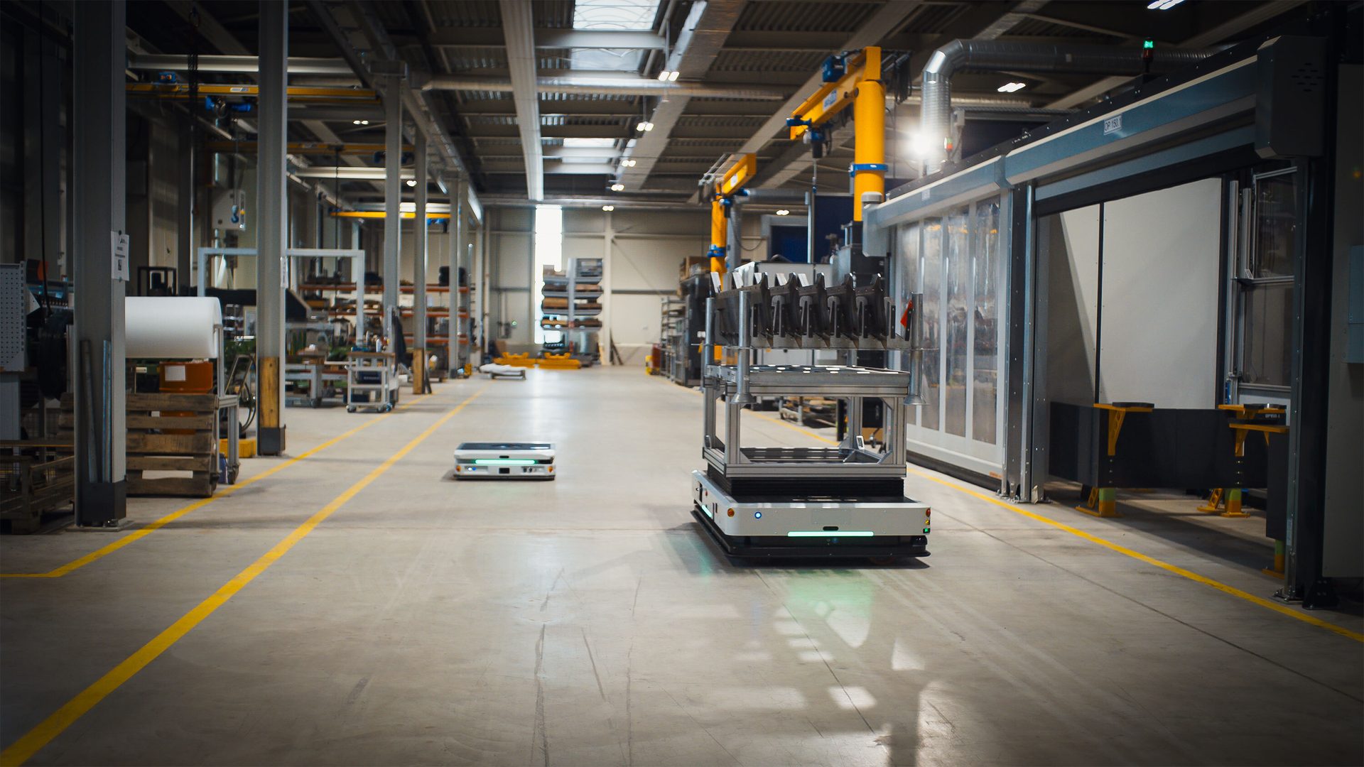 Two autonomous mobile robots (AMRs) navigate a factory floor with marked paths.