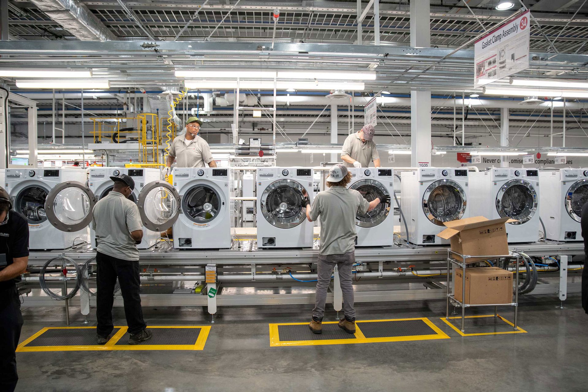 Workers assemble washing machines on a factory line.