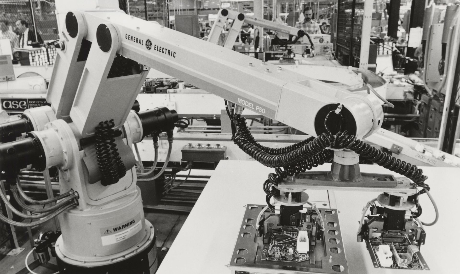 GE Model P50 industrial robot assembling circuit boards in a factory.