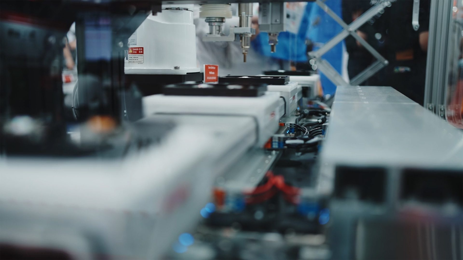 Close-up of an automated manufacturing assembly line with robotic components, conveyor belts, and warning labels.