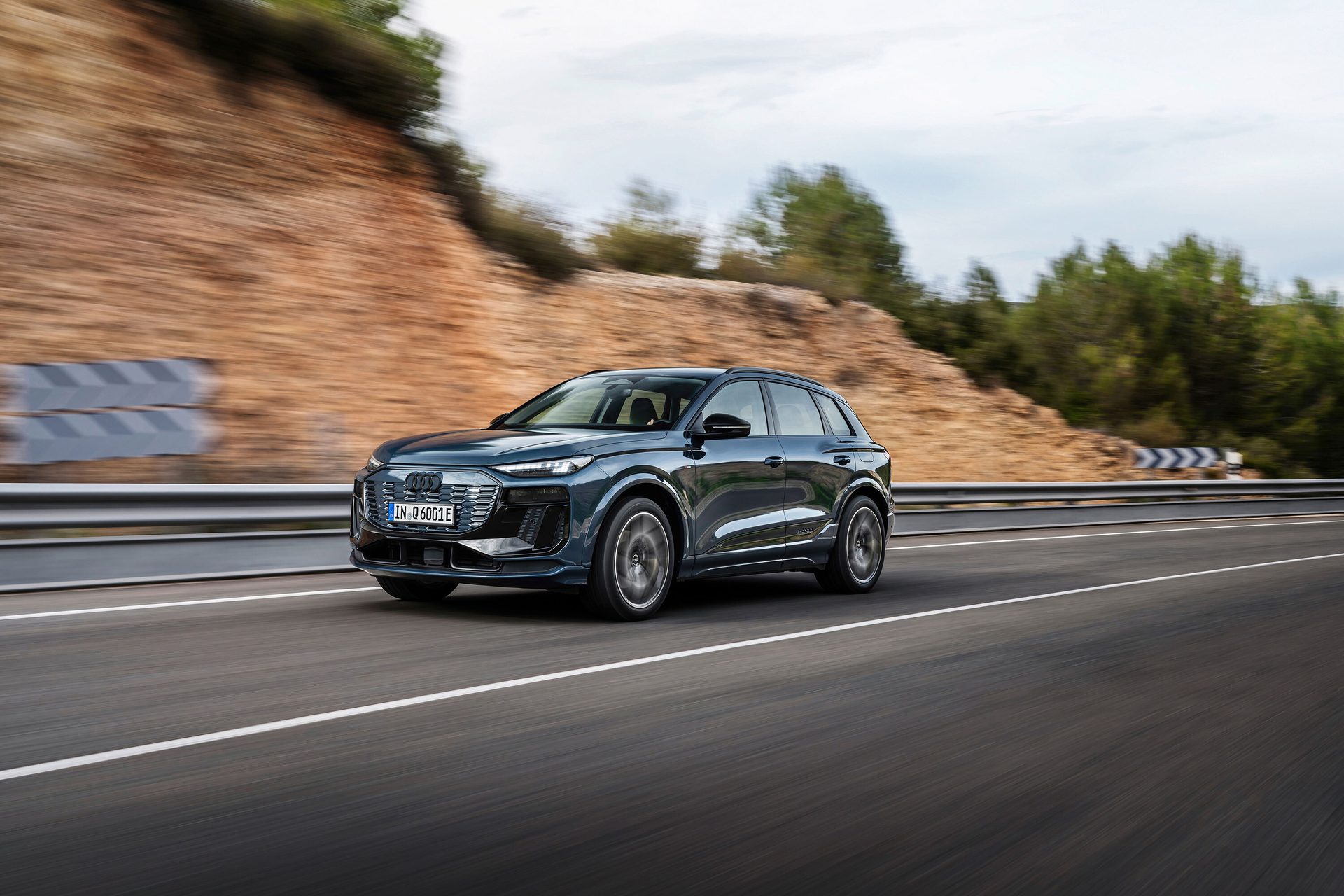 Dark blue Audi Q6 e-tron SUV driving dynamically on a road with motion blur.