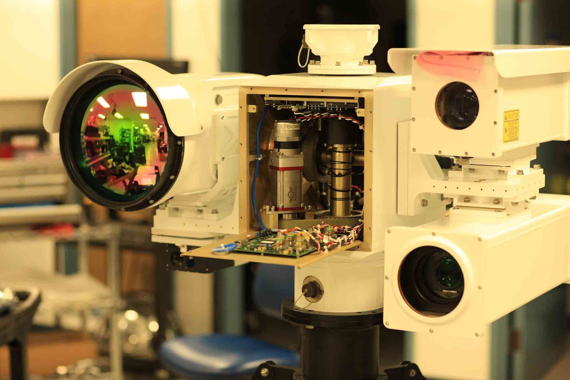 White optical system with large reflective lens, exposed circuits, and camera units.