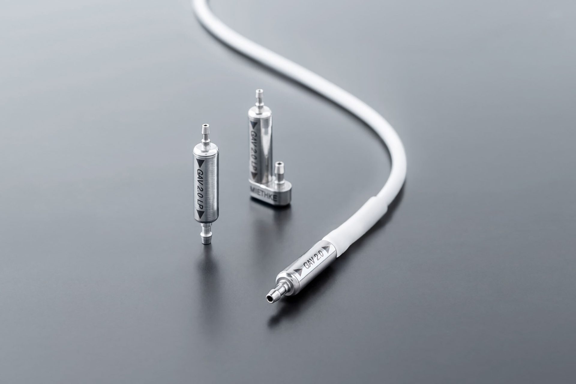 Three silver GAV 2.0 labeled components, two freestanding and one connected to a white cable.