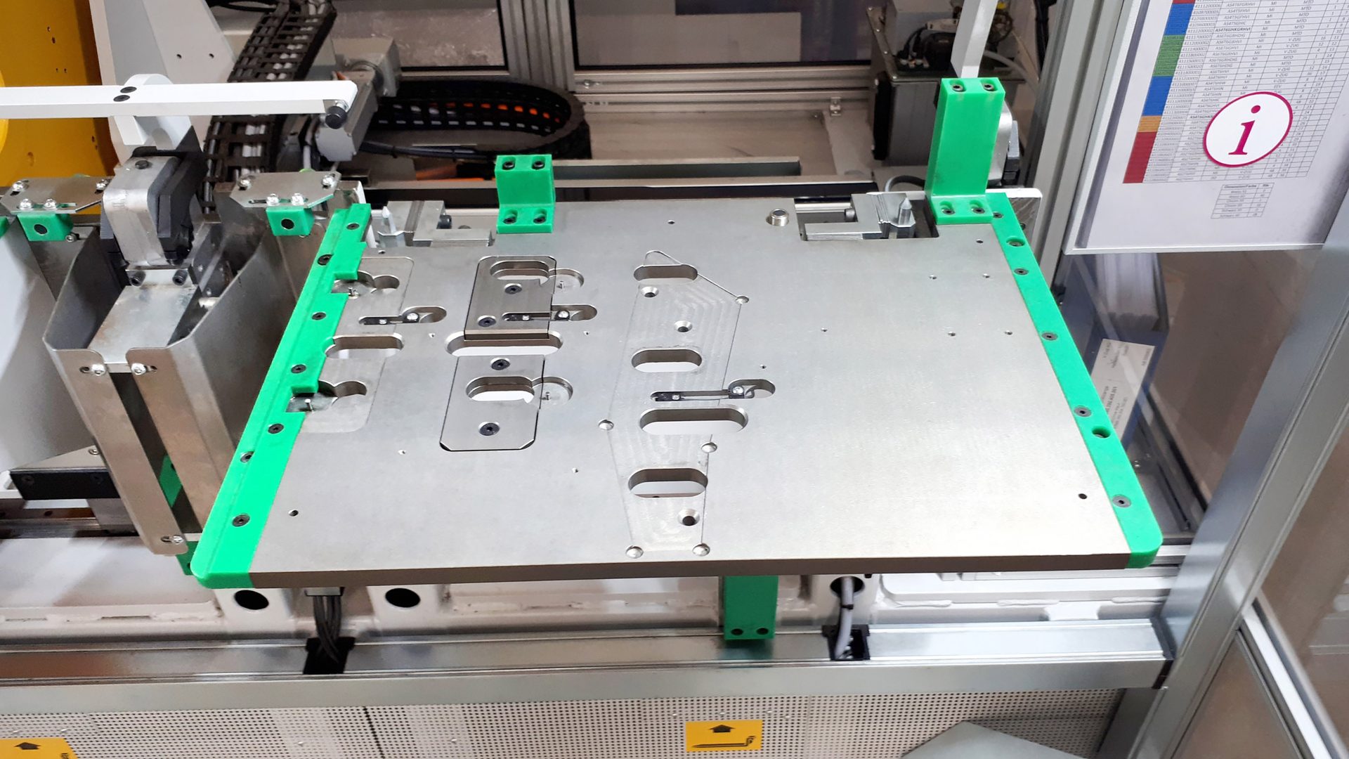 Metal fixture with green guides on an industrial machine.