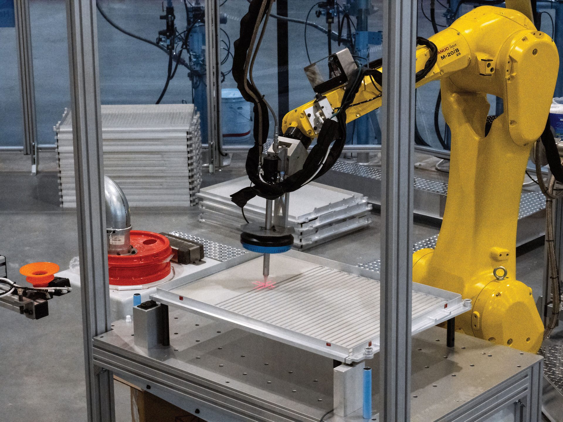 Yellow robot arm uses a laser to process a part on an assembly line.