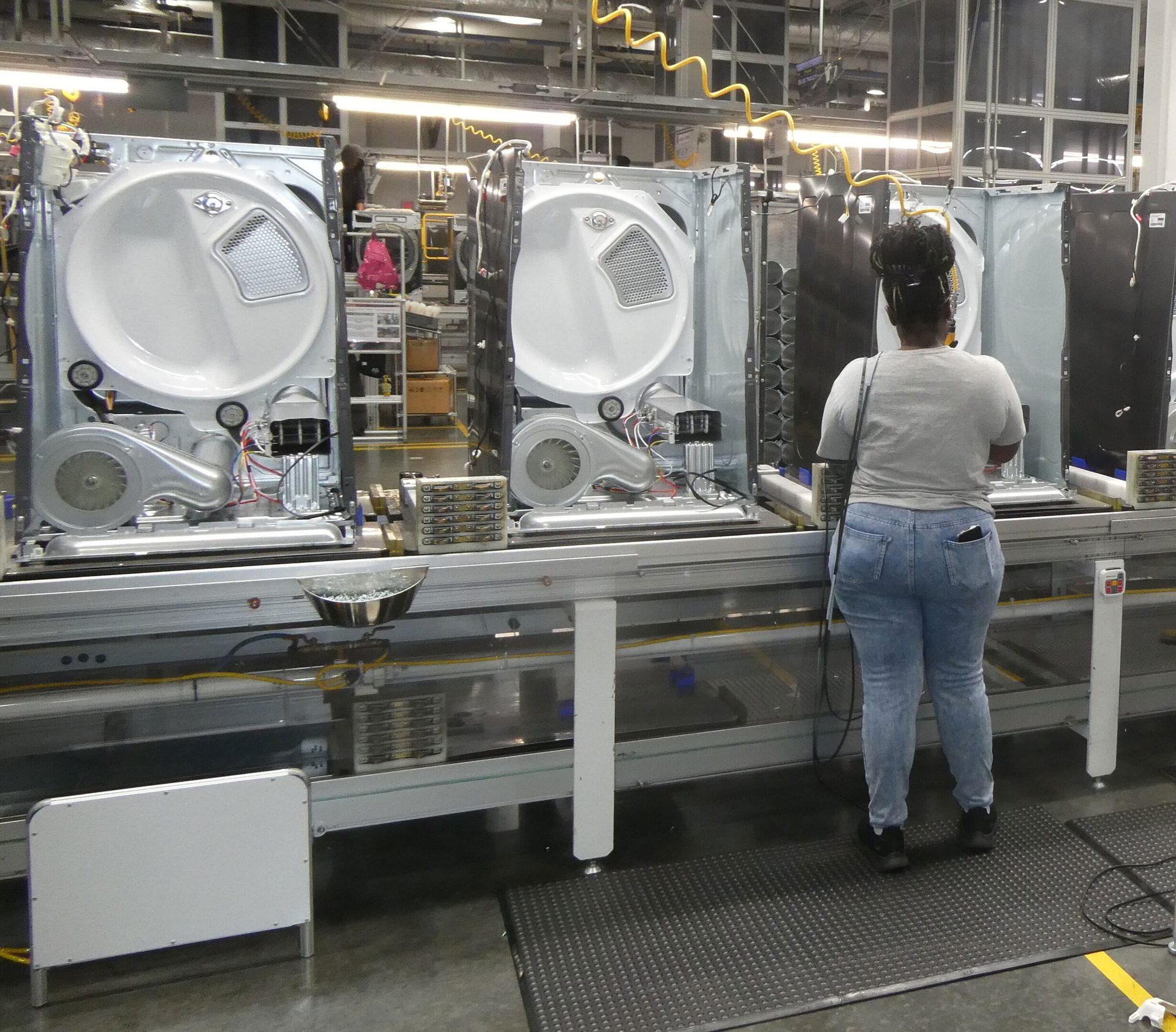 Worker assembling dryers on a factory production line.