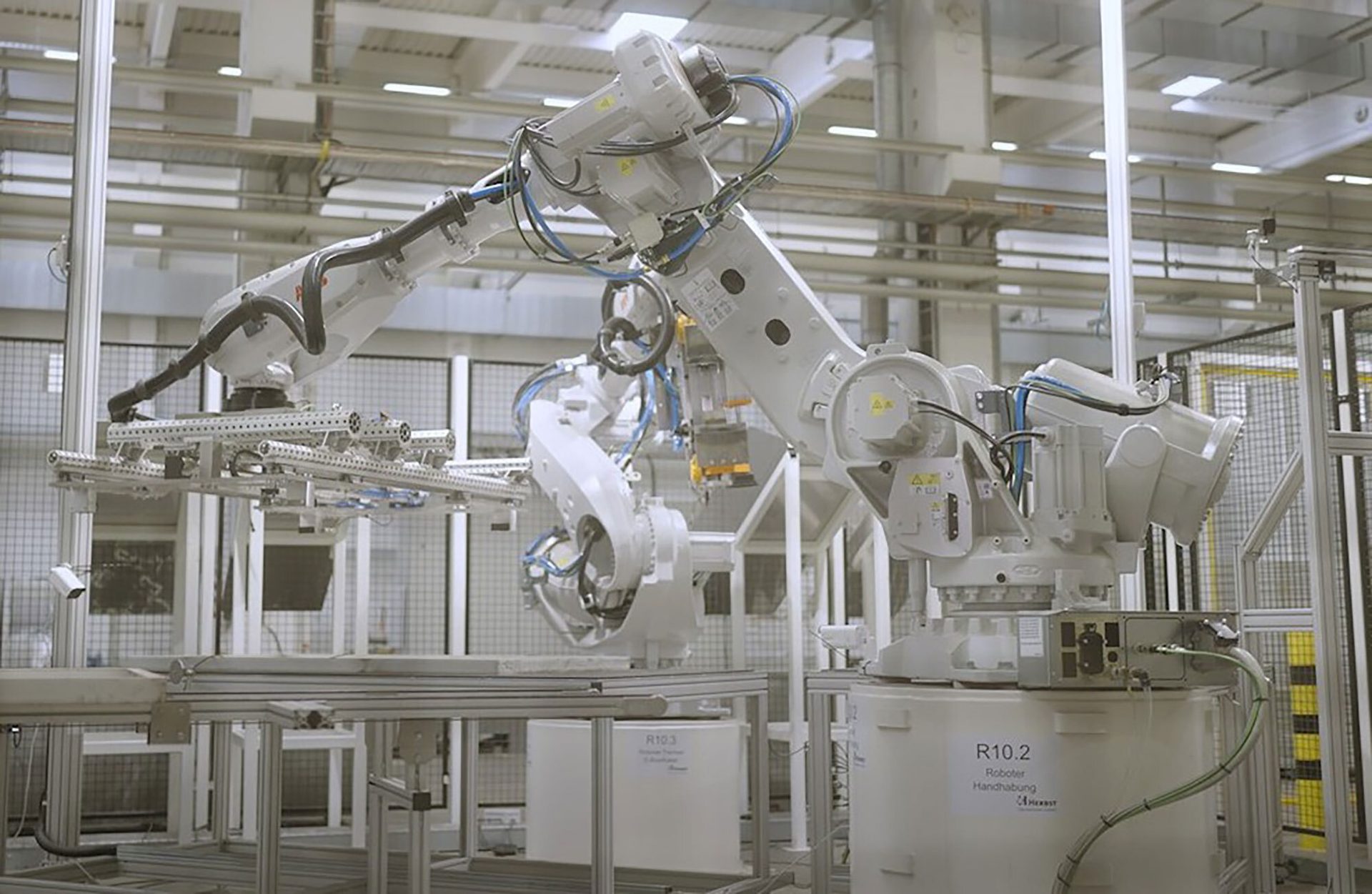White industrial robots with grippers on an assembly line.