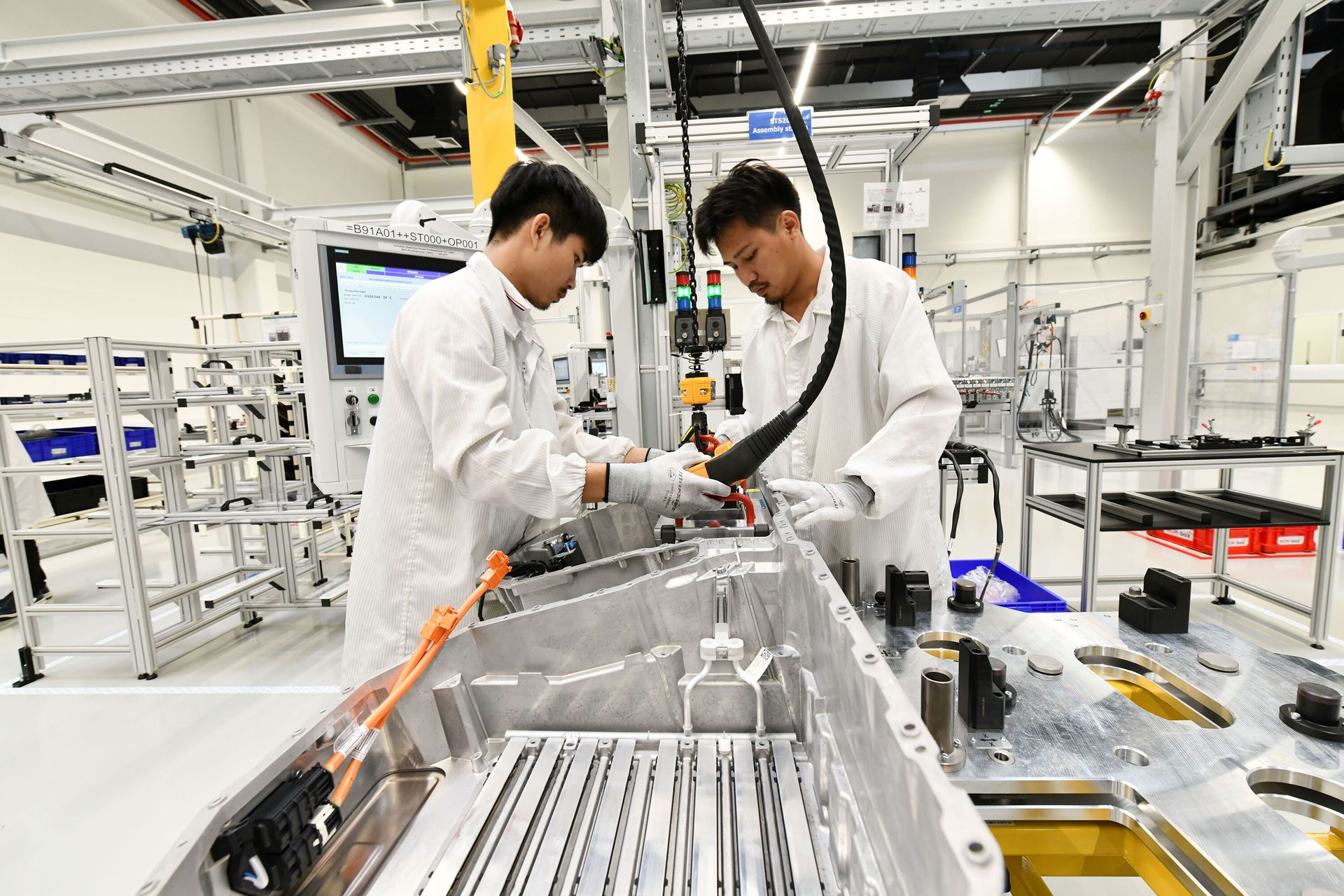 Two workers assembling a large metal component in a clean factory.