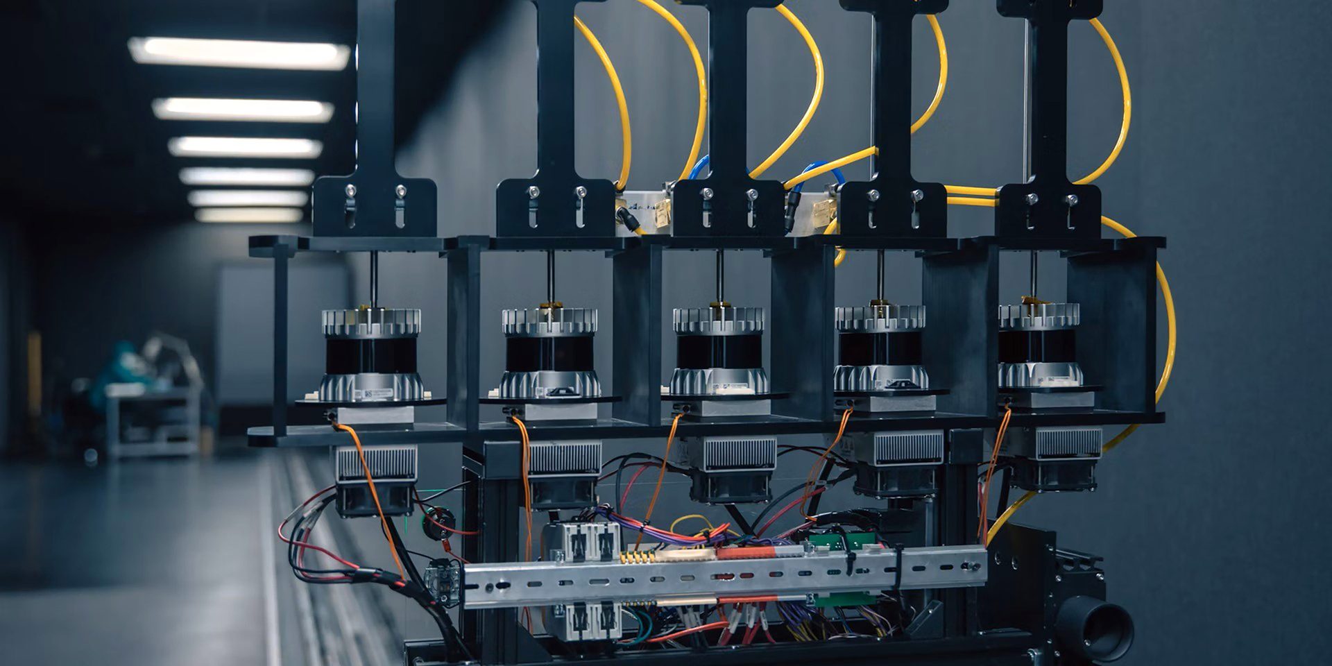 A row of four identical machines with black frames, silver components, yellow tubes, and visible wiring.