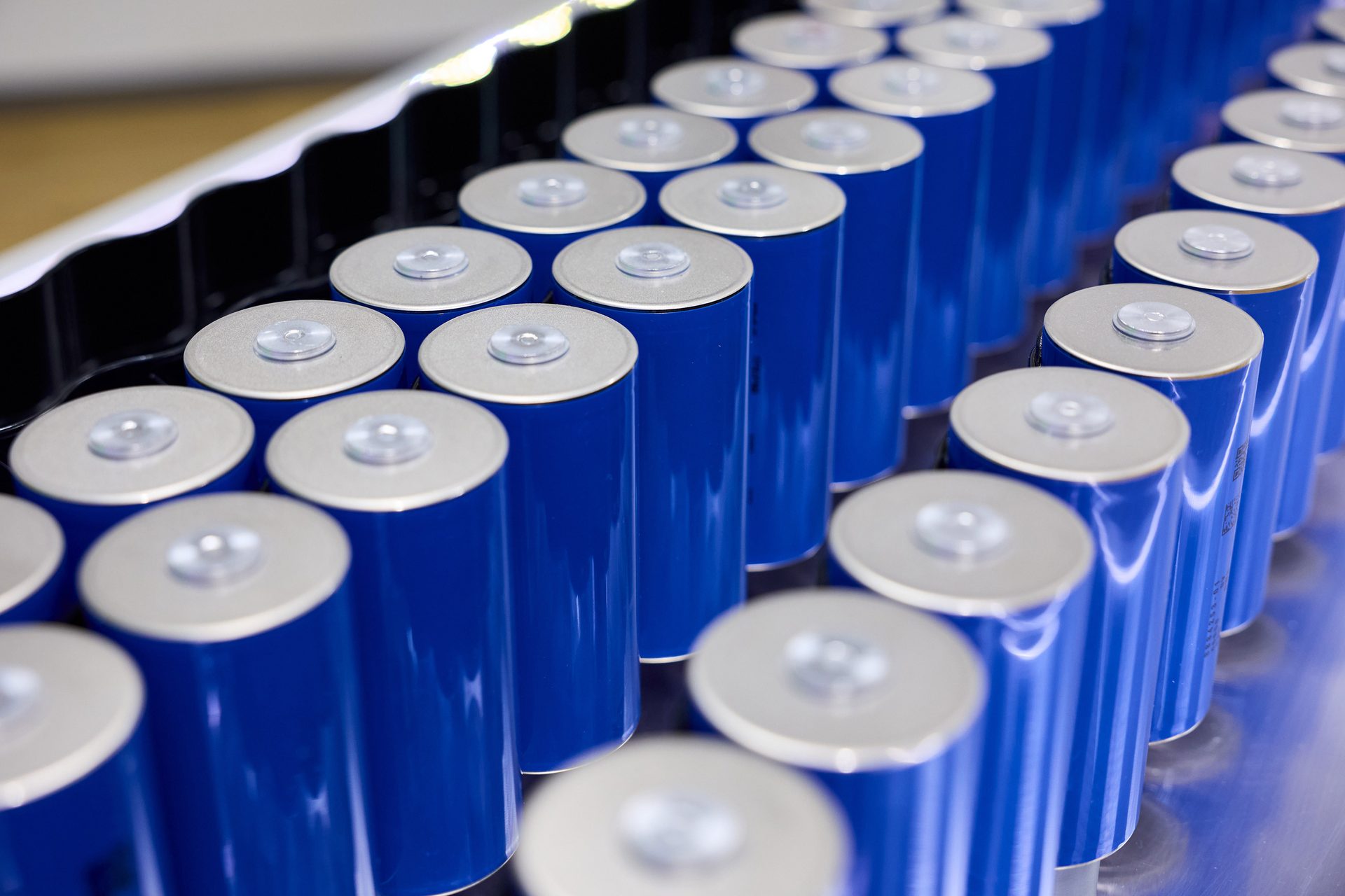 Rows of blue cylindrical batteries with silver tops.