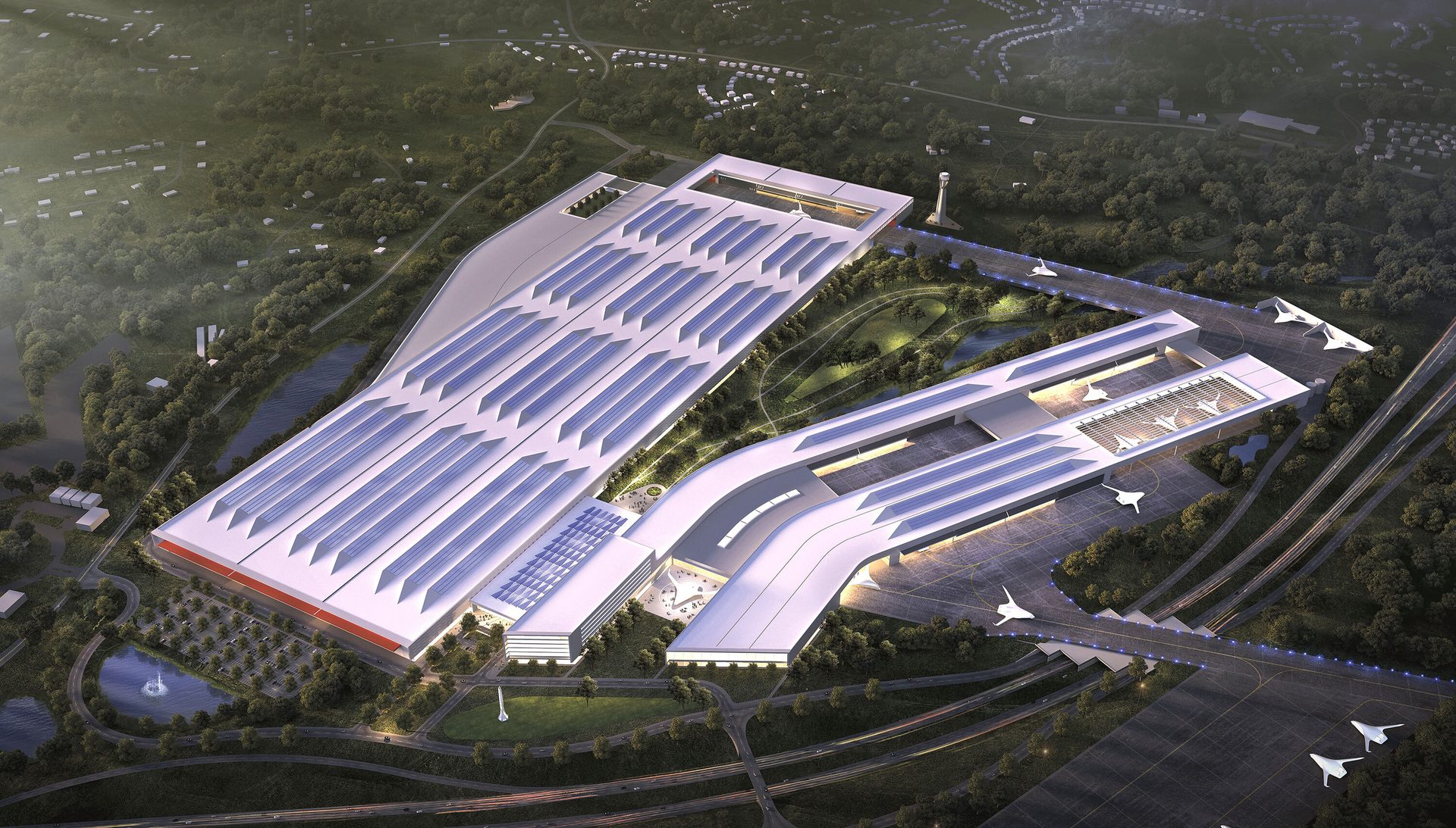 Aerial: large, modern aerospace factory with solar panel roofs and futuristic jets in green landscape.