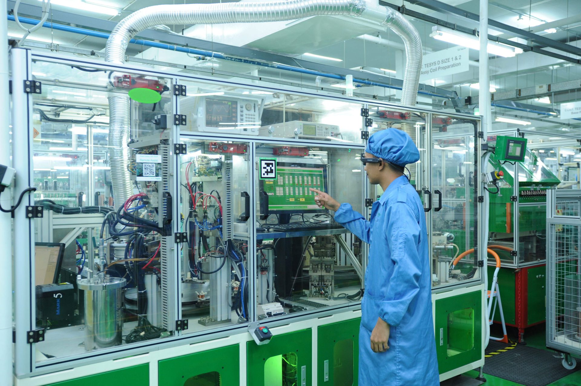 Worker in cleanroom with smart glasses interacting with a complex industrial machine's screen.