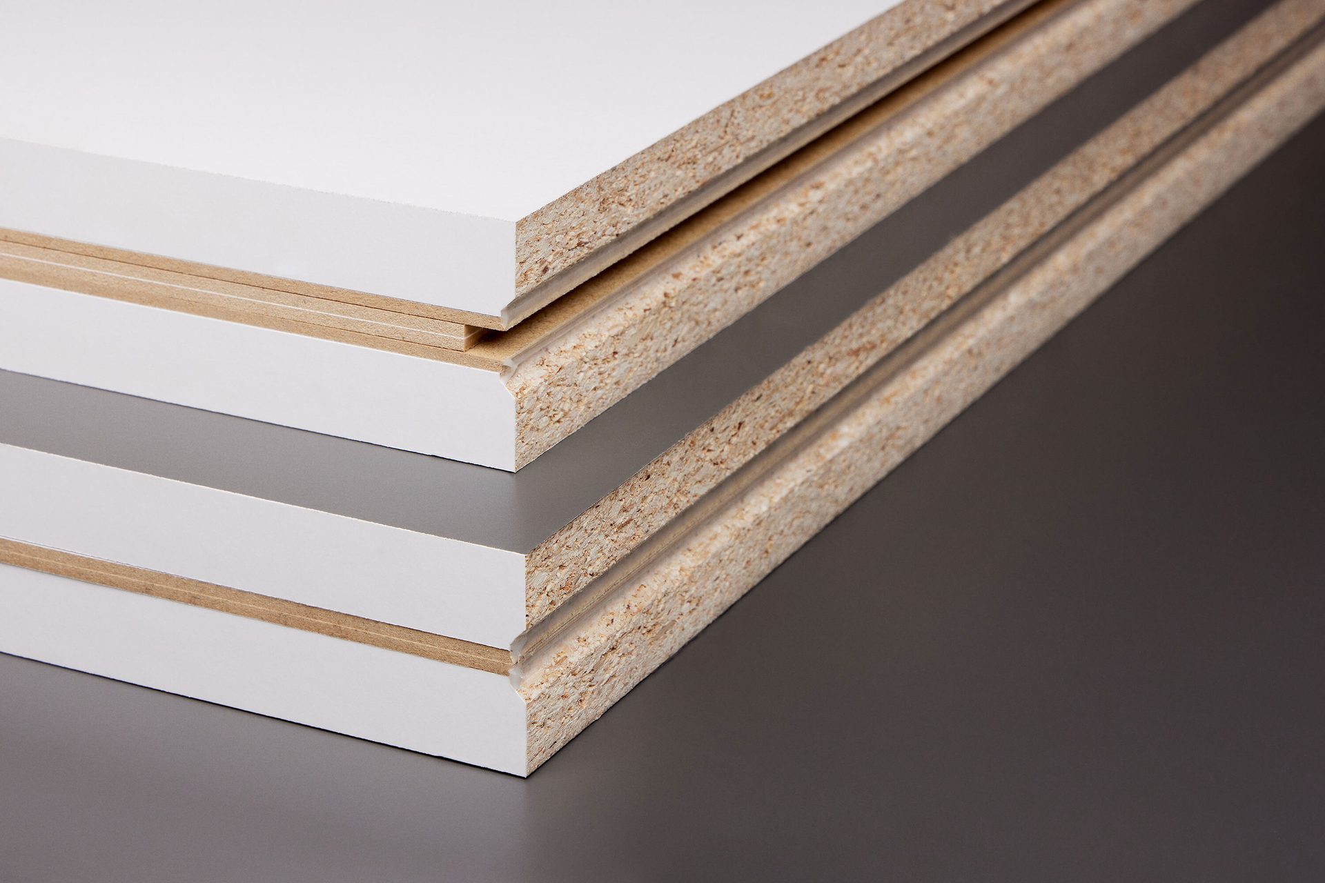 Stacked white and gray laminated chipboard panels, showing raw edges and layered construction.