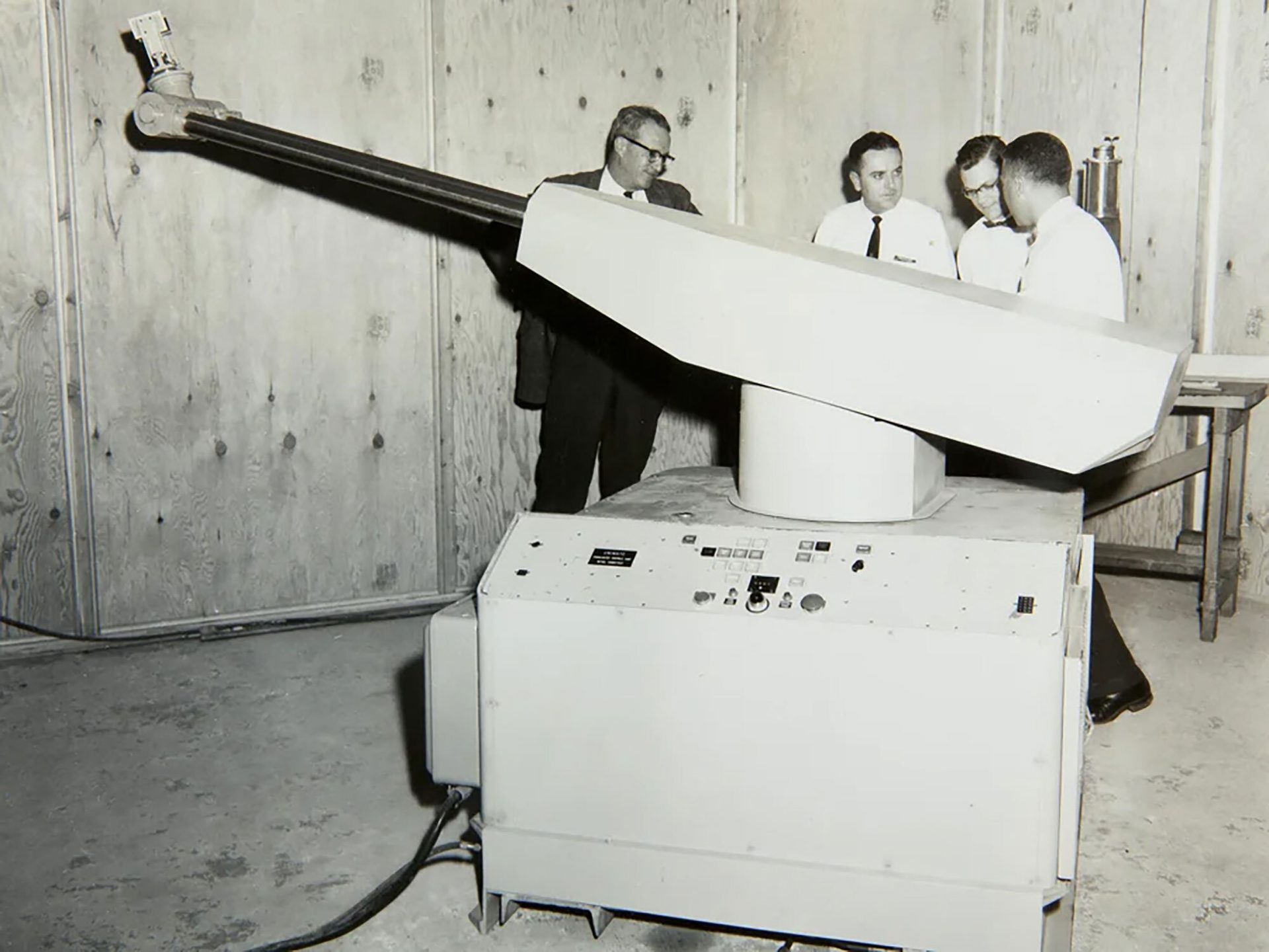 Four men examining a large, articulated scientific apparatus.