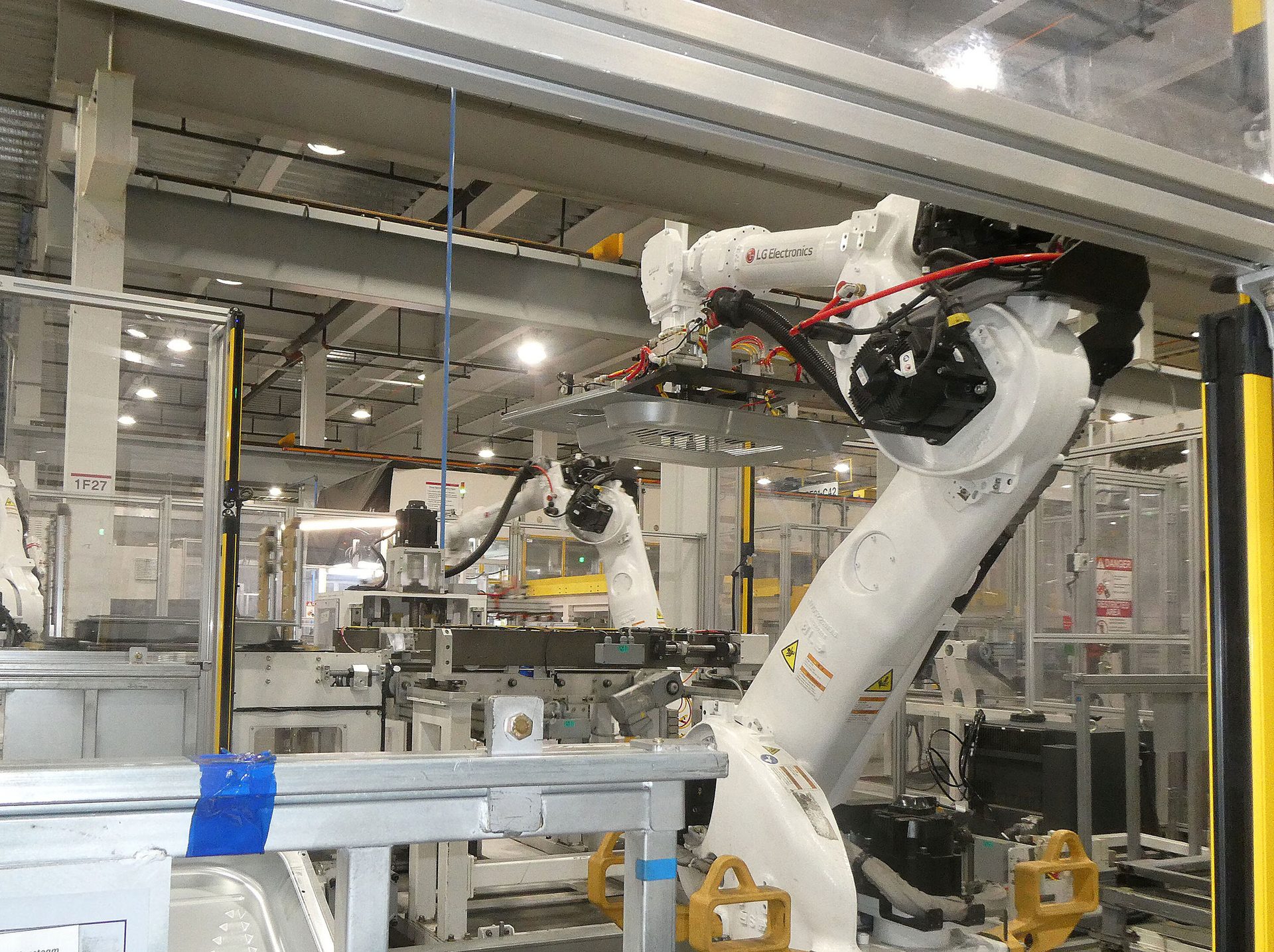 LG Electronics industrial robots on a factory floor, surrounded by manufacturing equipment.