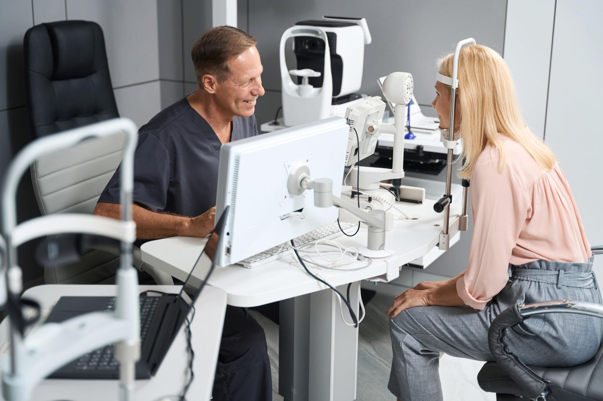 Optometrist conducting an eye exam on a female patient using advanced ophthalmology equipment in a clinic.