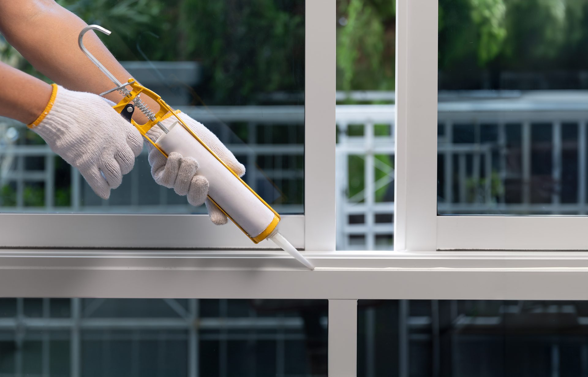 Construction worker using silicone sealant caulk for repair leaked inside window frame