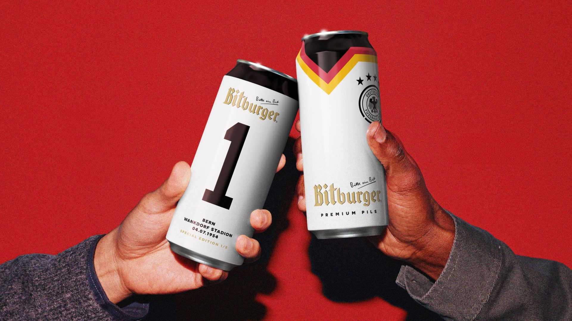 two hands holding DFB-themed Bitburger cans against red background
