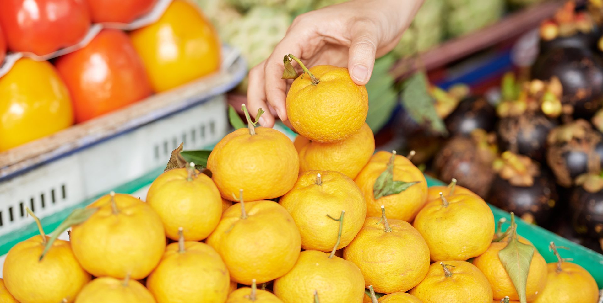 Hand of a customer taking one tangerine from the pile 