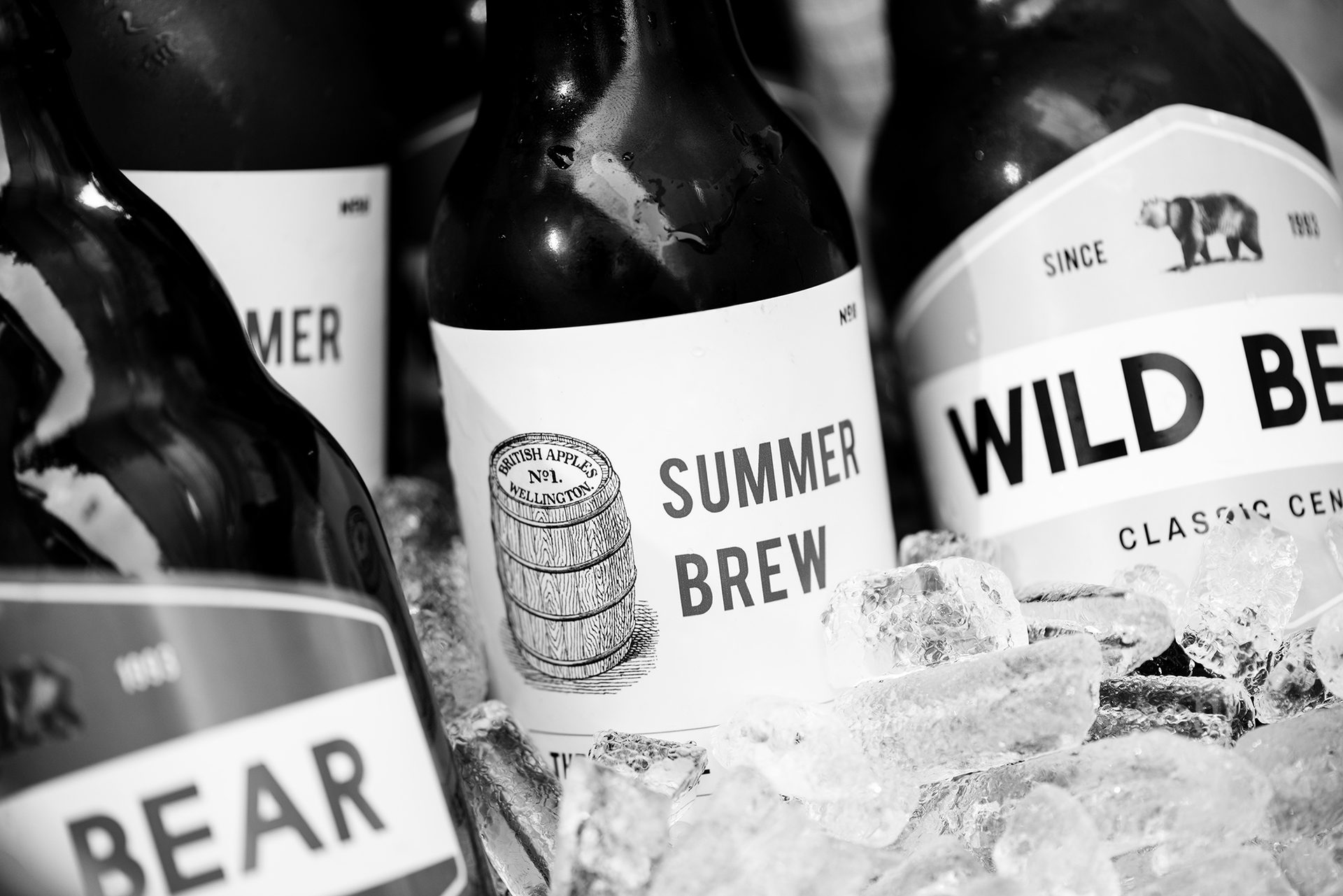 Black-and-white image of bottles of beer chilling in ice.