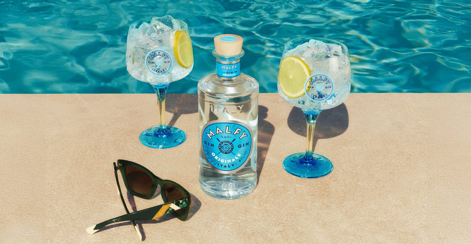Malfy Originale bottle, with glasses on each side of it, poolside