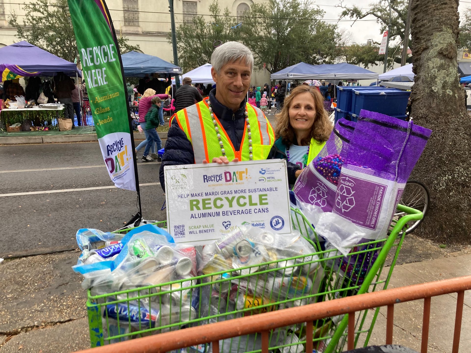 Two volunteers with empty cans they collected from Mardi Gras parade-goers