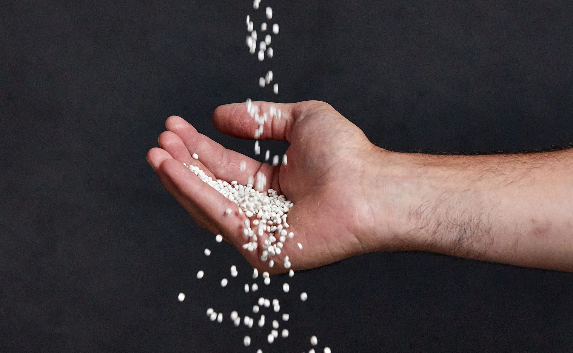 Image of hand catching falling pellets made of recycled polyethylene (rPE).