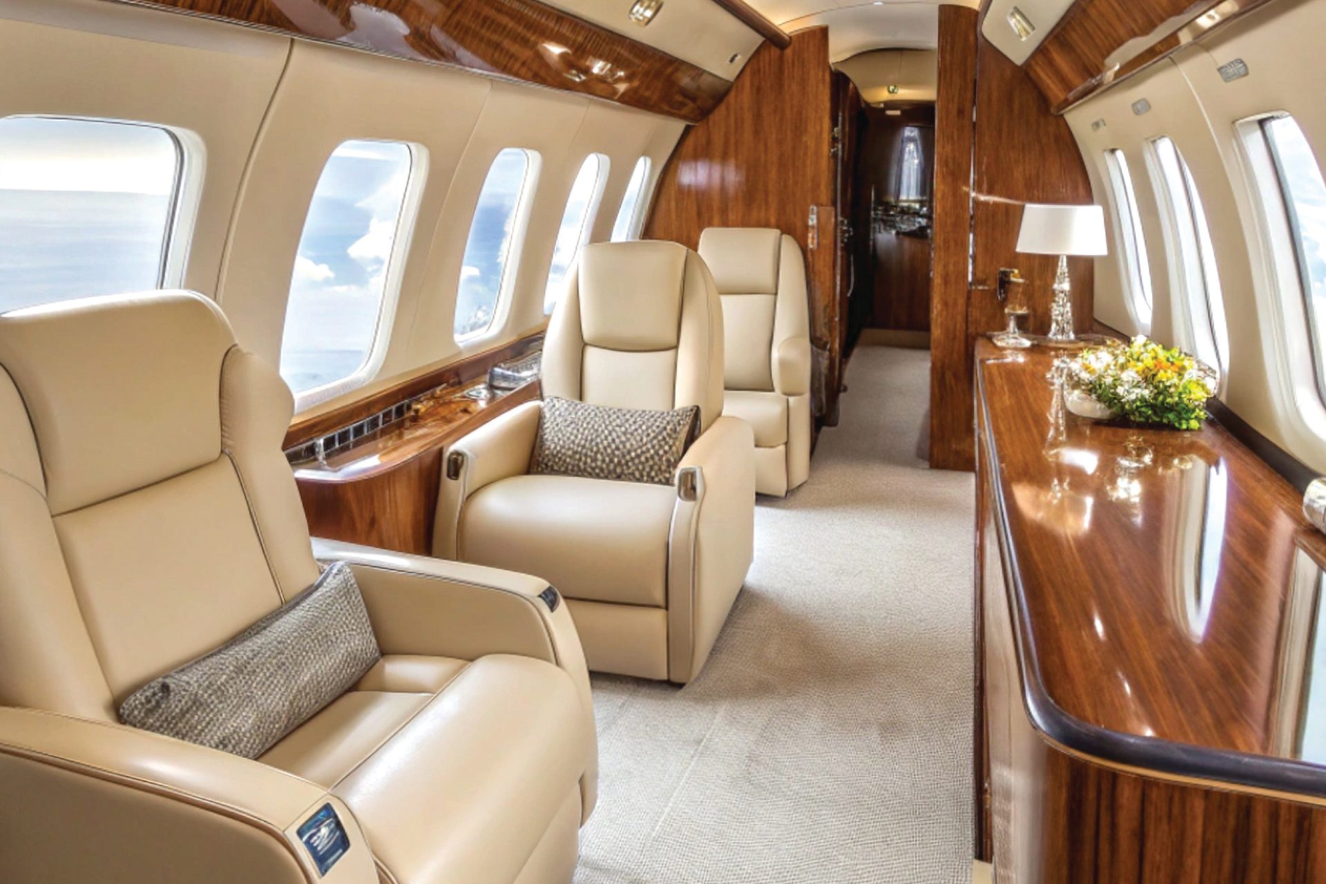 Luxurious private jet interior with beige leather seats, polished wood trim, and scenic windows.